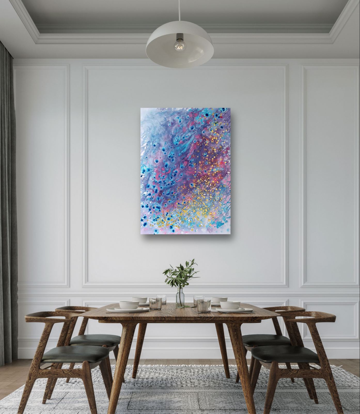 Award-winning original spiritual abstract painting Noise from Dreams by Diana Dimova TRAXI, fluid acrylic pouring in soft white, blue, rose and gold tones. An abstract canvas art print with vibrant blue, purple, and pink paint splatters hangs on a white paneled wall above a wooden dining table and chairs in a modern dining room.