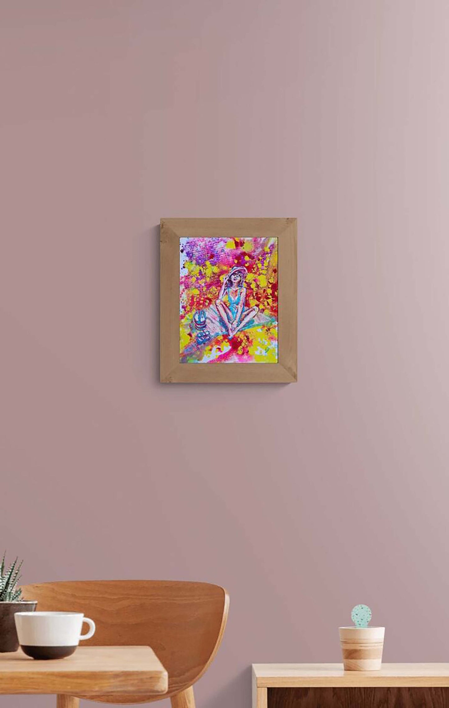 Wonderful Sunny Mood original acrylic pouring painting by Diana Dimova TRAXI ART, capturing an aura of light and summer energy. A framed colorful abstract painting hanging on a dusty mauve wall above a wooden chair and table in a modern room setting.