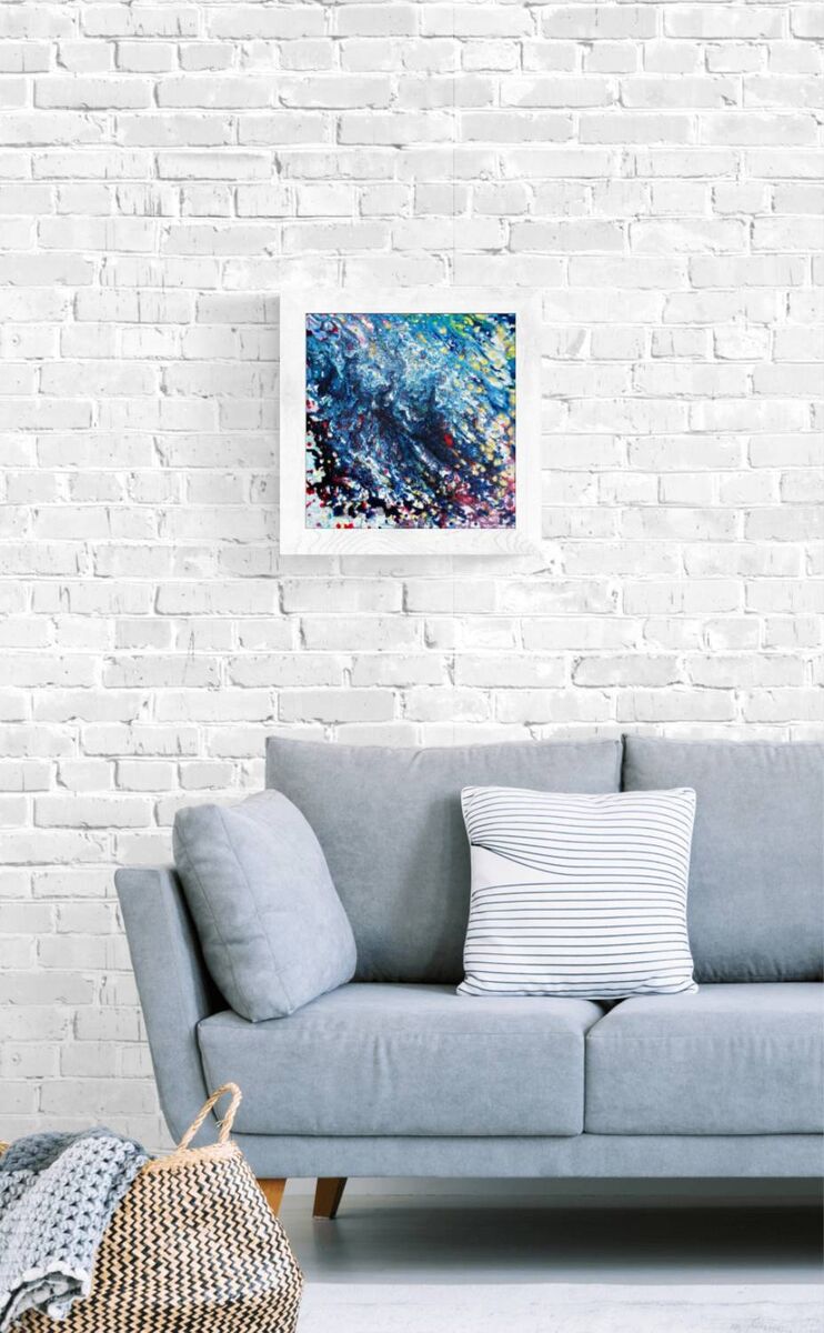 Arabian Nights original abstract painting in deep blue and purple by contemporary artist Diana Dimova TRAXI. A framed abstract art print featuring vibrant blue, purple, and white brushstrokes, displayed on a white brick wall above a light gray sofa with decorative pillows.