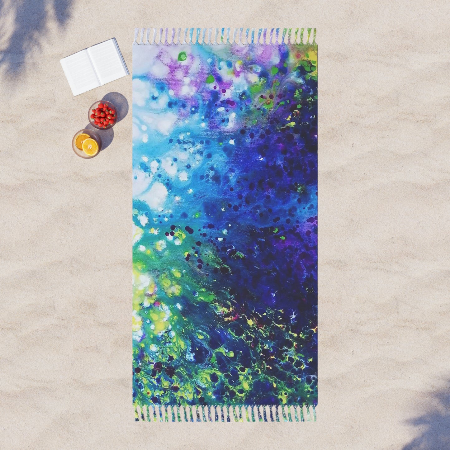 Aromatic lavender symphony boho beach towel featuring abstract wearable art inspired by the painting Aromatic Lavender Symphony by Diana Dimova TRAXI. A rectangular beach towel with fringed edges lies on light beige sand. The towel features a vibrant abstract fluid art pattern blending shades of blue, purple, green, and white.