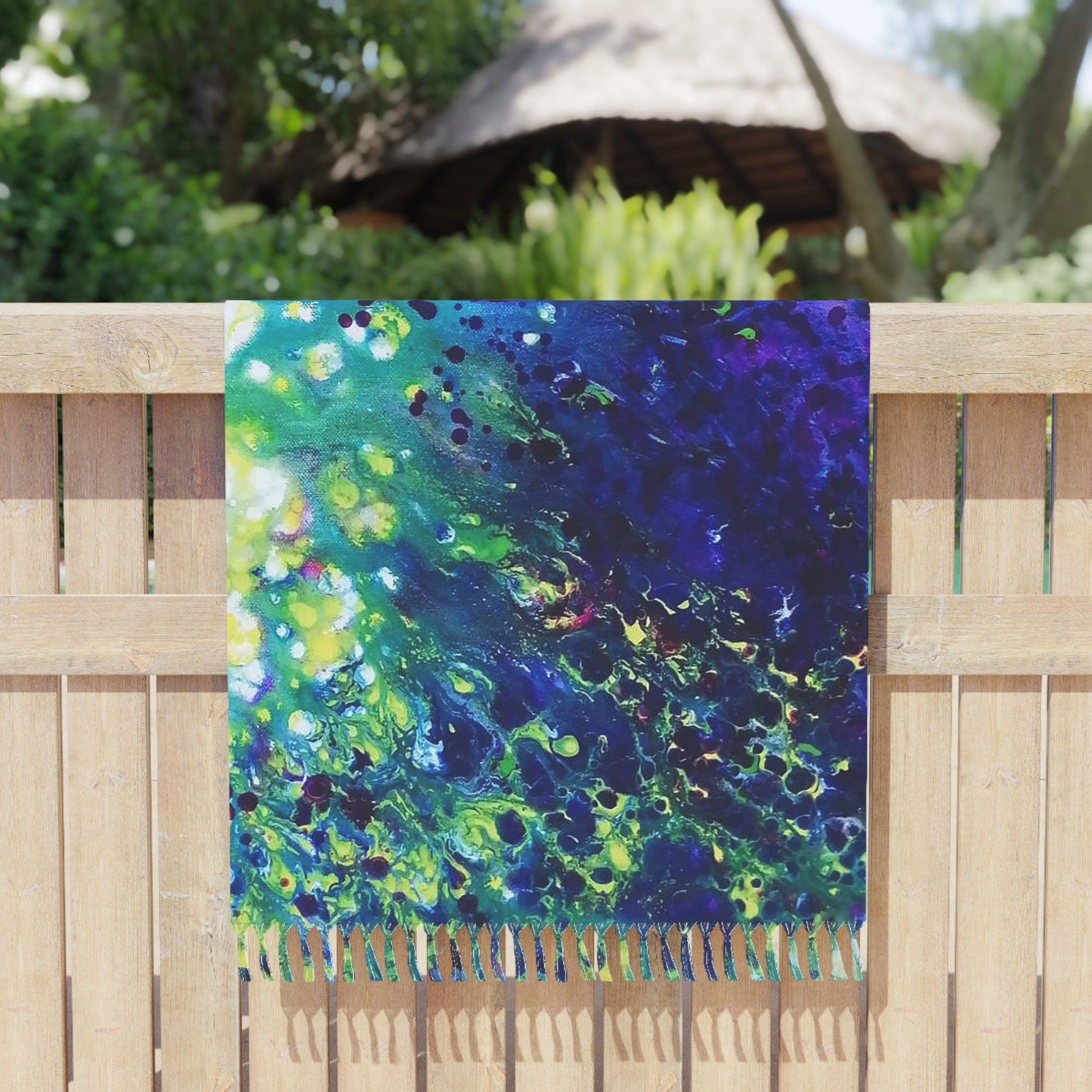 Aromatic lavender symphony boho beach towel featuring abstract wearable art inspired by the painting Aromatic Lavender Symphony by Diana Dimova TRAXI. A square scarf with a vibrant abstract fluid art pattern in shades of blue, green, and purple, draped over a light brown wooden fence with a blurred outdoor background.