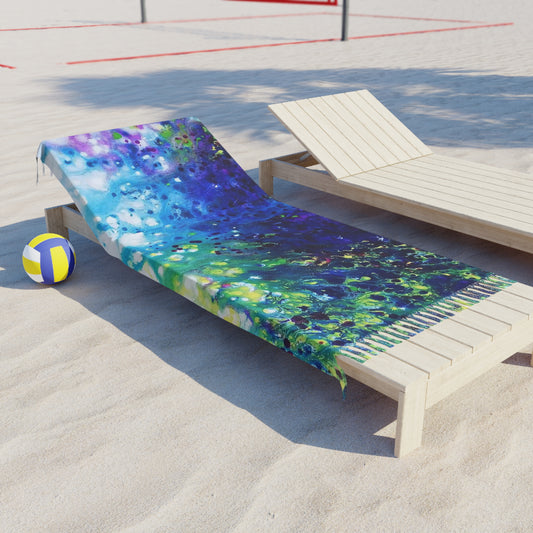 Aromatic lavender symphony boho beach towel featuring abstract wearable art inspired by the painting Aromatic Lavender Symphony by Diana Dimova TRAXI. A colorful beach towel with a vibrant blue, green, and purple watercolor design is draped over a light wood beach lounge chair on a sandy volleyball court. A yellow and blue volleyball sits on the sand nearby.