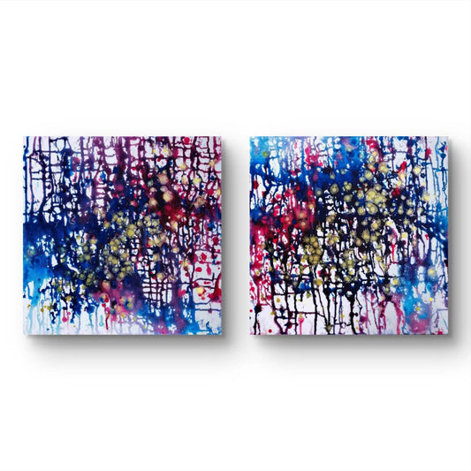 Award-winning abstract diptych Greed and Fear by Diana Dimova TRAXI, fluid acrylic pouring in white, blue, rose and gold tones Two square abstract wall art panels with colorful paint splatters and drips on a white background, shown side by side.