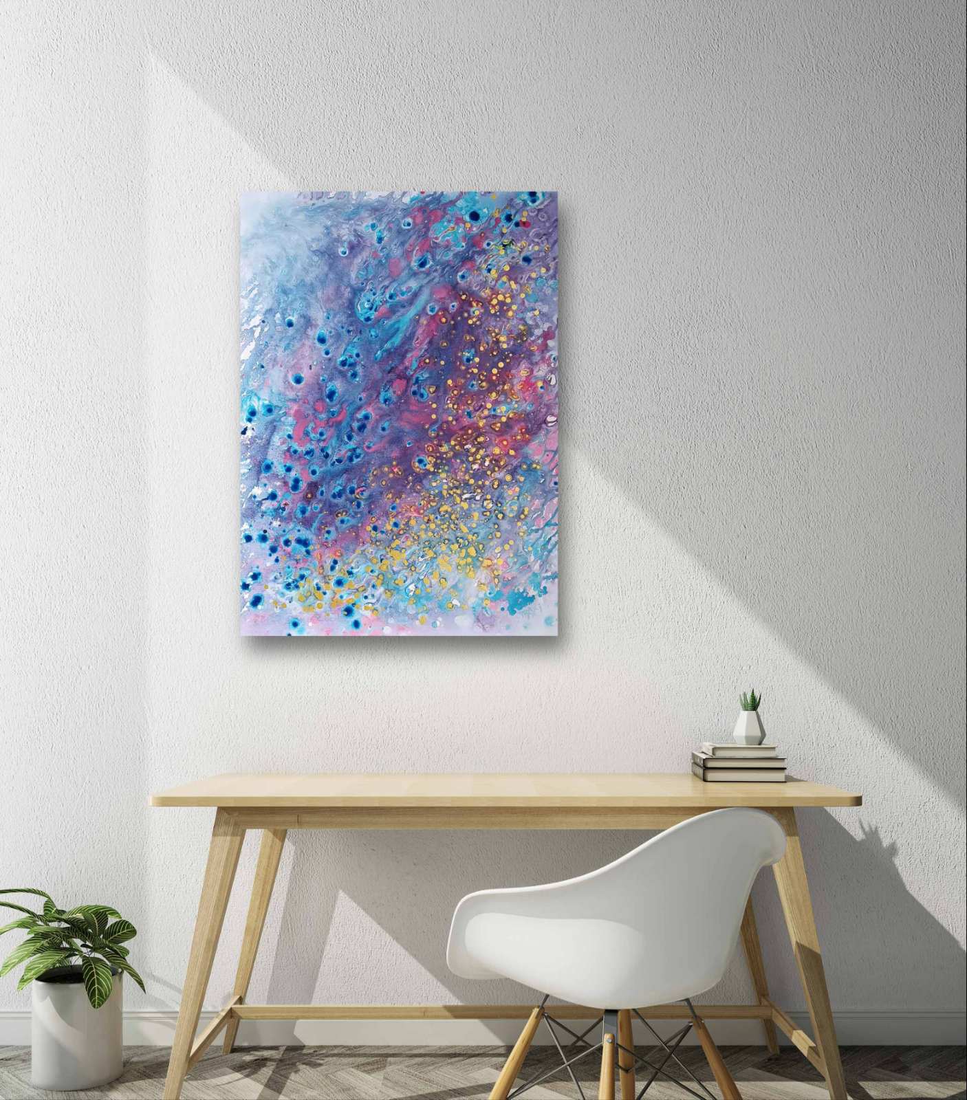 Award-winning original spiritual abstract painting Noise from Dreams by Diana Dimova TRAXI, fluid acrylic pouring in soft white, blue, rose and gold tones. Abstract canvas wall art featuring a colorful paint splatter pattern in shades of blue, purple, pink, and gold, displayed on a white wall above a light wood desk and white chair.
