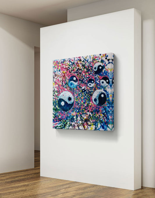 Yin Yang spiritual abstract painting titled Events of Life by Diana Dimova TRAXI featuring a circular blue, white, and soft pink composition for modern luxury interiors. A square abstract canvas wall art print featuring stylized yin-yang faces over a colorful, textured background, displayed on a white gallery wall in a modern room with wood floors.