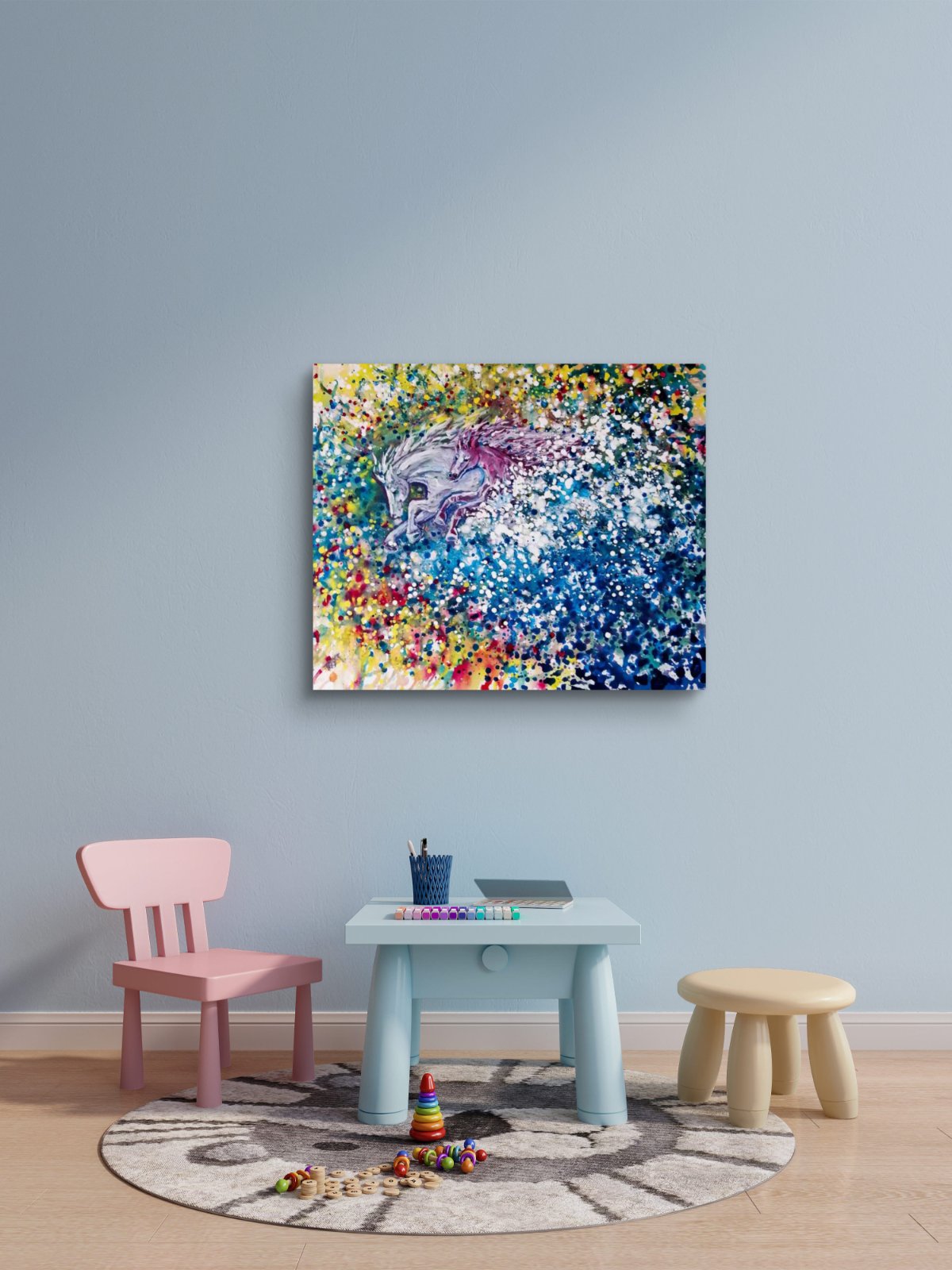 Freedom in color abstract horse original painting by contemporary artist TRAXI, featuring twin horses galloping through a vibrant cosmic nebula sky. A colorful abstract canvas print of a unicorn is displayed on a light blue wall in a children's playroom setting, above a light blue table, pink chair, and small stool.