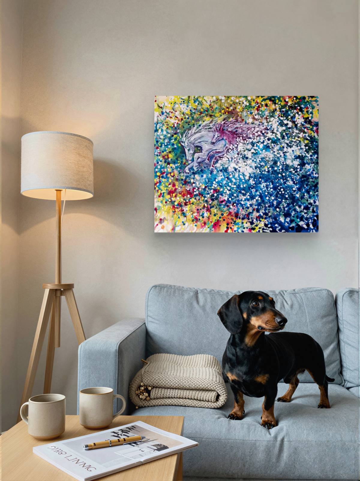 Freedom in color abstract horse original painting by contemporary artist TRAXI, featuring twin horses galloping through a vibrant cosmic nebula sky. A colorful abstract canvas print featuring a horse head surrounded by vibrant paint splatters, displayed on a light gray wall above a blue-gray sofa with a dachshund dog and a floor lamp in a cozy living room setting.