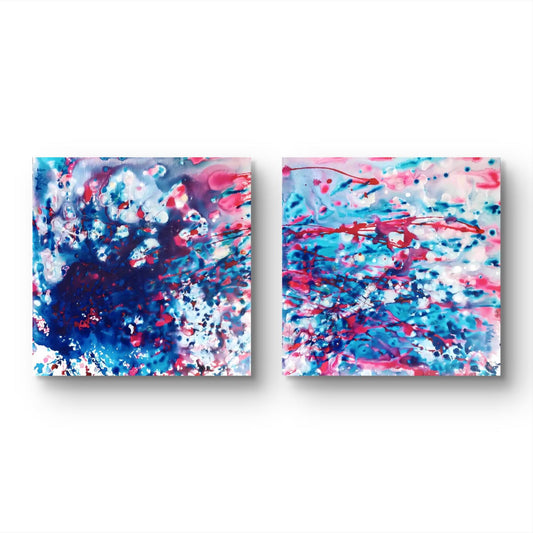 Limited edition canvas print diptych Theory of Attraction by Diana Dimova TRAXI, featuring blue, white, and rose tones exploring manifestation and cosmic synchronicity. Two square abstract wall art panels with a colorful paint-splatter design in blue, pink, white, and purple, displayed side by side on a white background.