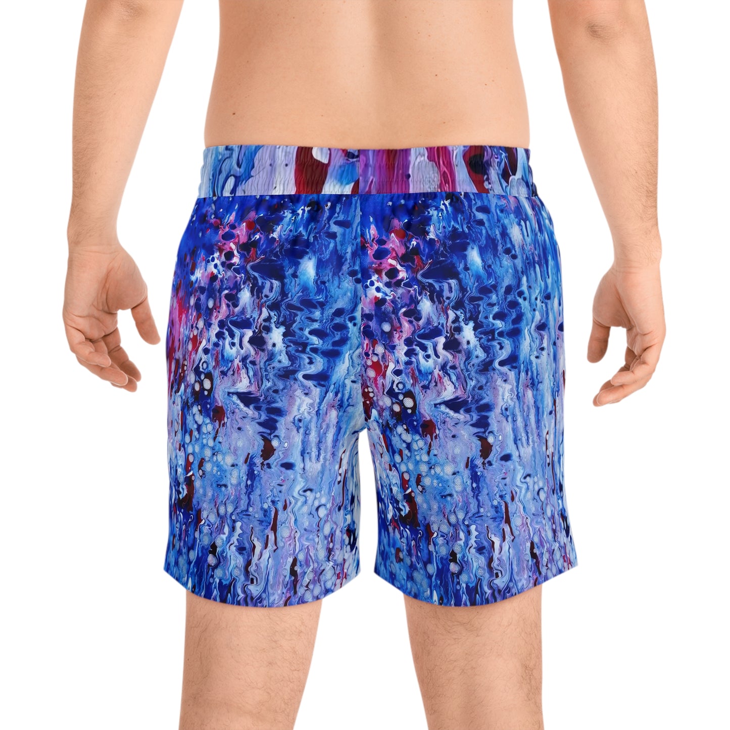 Men's blue ocean swim shorts featuring wearable art inspired by blue underwater paintings by Diana Dimova TRAXI. A man wearing swim trunks with an abstract blue, purple, and white paint-splatter pattern, shown from the back against a plain white background.