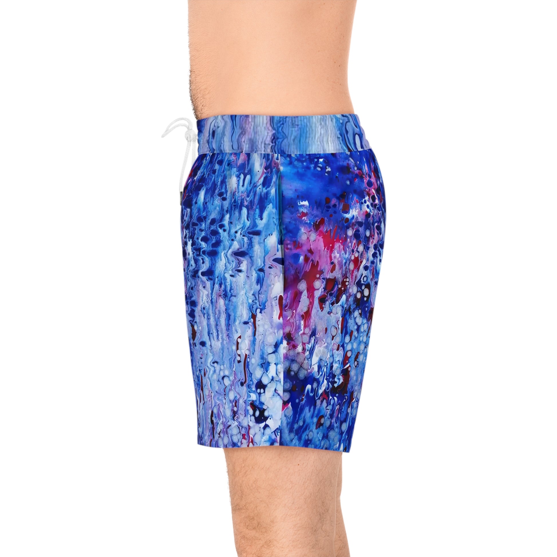 Men's blue ocean swim shorts featuring wearable art inspired by blue underwater paintings by Diana Dimova TRAXI. Men's swim trunks with an abstract blue, purple, and pink paint-splatter pattern, shown on a model from the waist to mid-thigh against a white background.