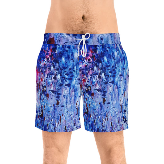 Men's blue ocean swim shorts featuring wearable art inspired by blue underwater paintings by Diana Dimova TRAXI. Men's swim trunks with an abstract blue, purple, and white paint-splatter pattern, featuring a white drawstring waist, modeled on a person against a white background.