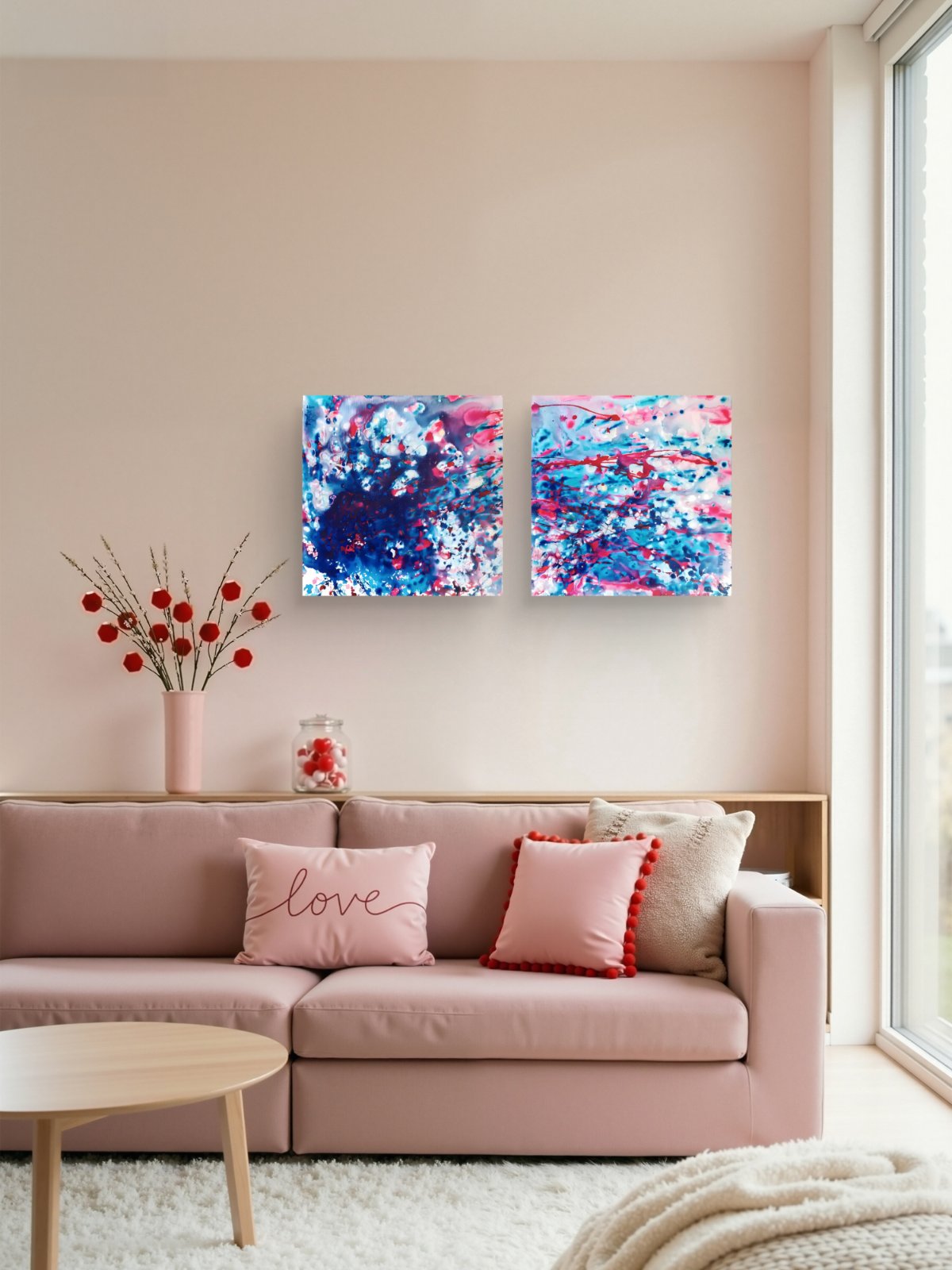 Original abstract diptych Theory of Attraction by Diana Dimova TRAXI, featuring blue, white, and rose tones exploring manifestation and cosmic synchronicity. A modern living room scene featuring a light pink sectional sofa with decorative pillows, a round wooden coffee table, and two square abstract canvas prints in blue, pink, and white hanging on the wall above the sofa.