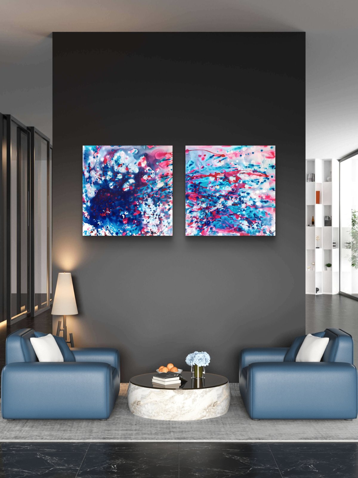 Original abstract diptych Theory of Attraction by Diana Dimova TRAXI, featuring blue, white, and rose tones exploring manifestation and cosmic synchronicity. A modern living room setting featuring two square abstract canvas paintings with vibrant blue, pink, and white paint strokes, hung side-by-side on a dark gray wall above two blue armchairs and a round marble coffee table.