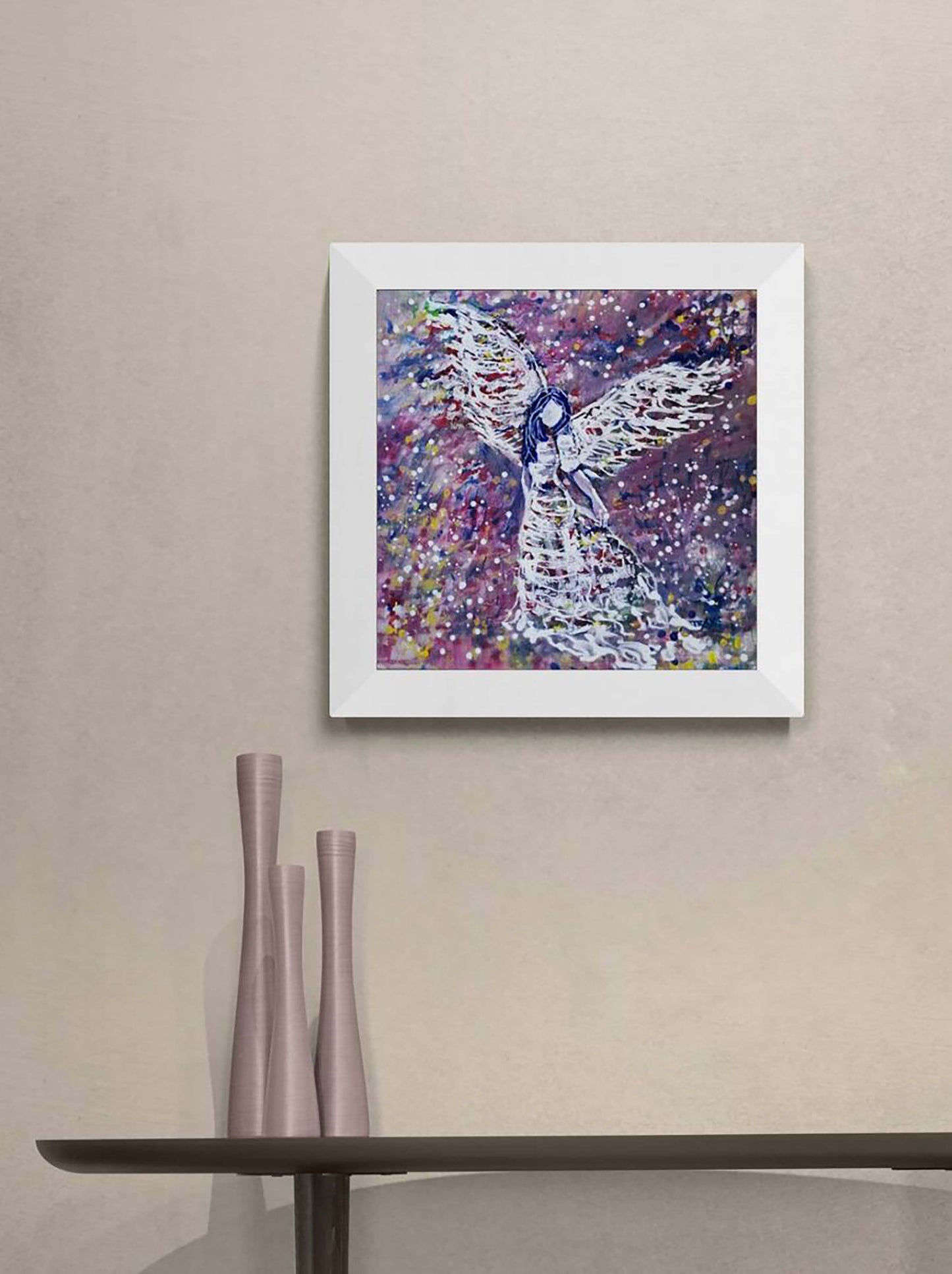 Original abstract figurative painting White Angel by Diana Dimova TRAXI, featuring spiritual symbolism in purple and white tones. A framed abstract painting of an angel with outstretched wings, featuring a textured purple, pink, and blue background, displayed on a beige wall above a console table with three vases.