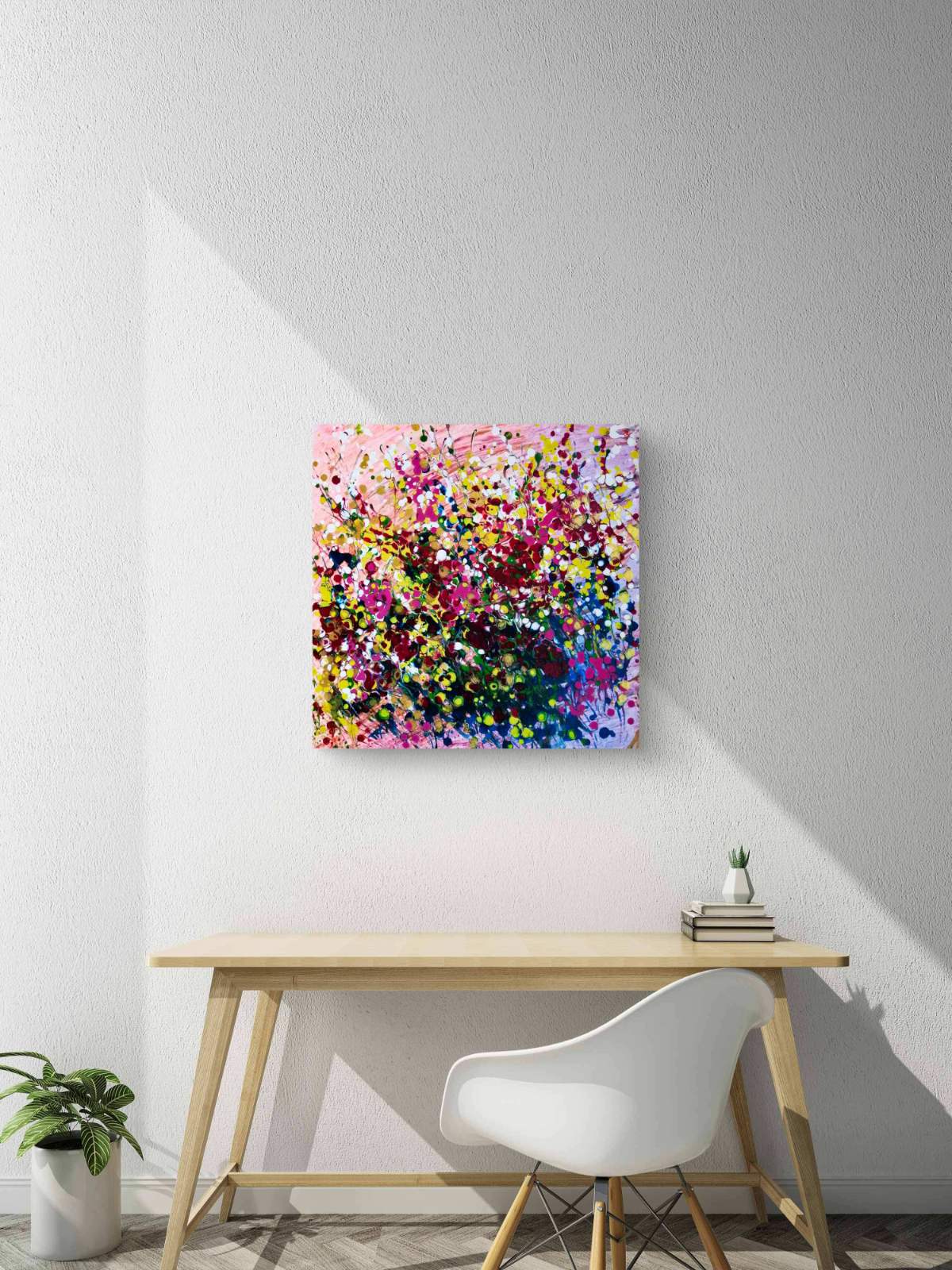 Original abstract painting Summer Garden Flowers by Diana Dimova TRAXI, featuring a colorful floral bouquet in vibrant yellow, pink, and orange tones. A colorful abstract canvas print featuring a dense, multicolored floral or textured pattern, displayed on a light gray wall above a wooden desk with a white chair.