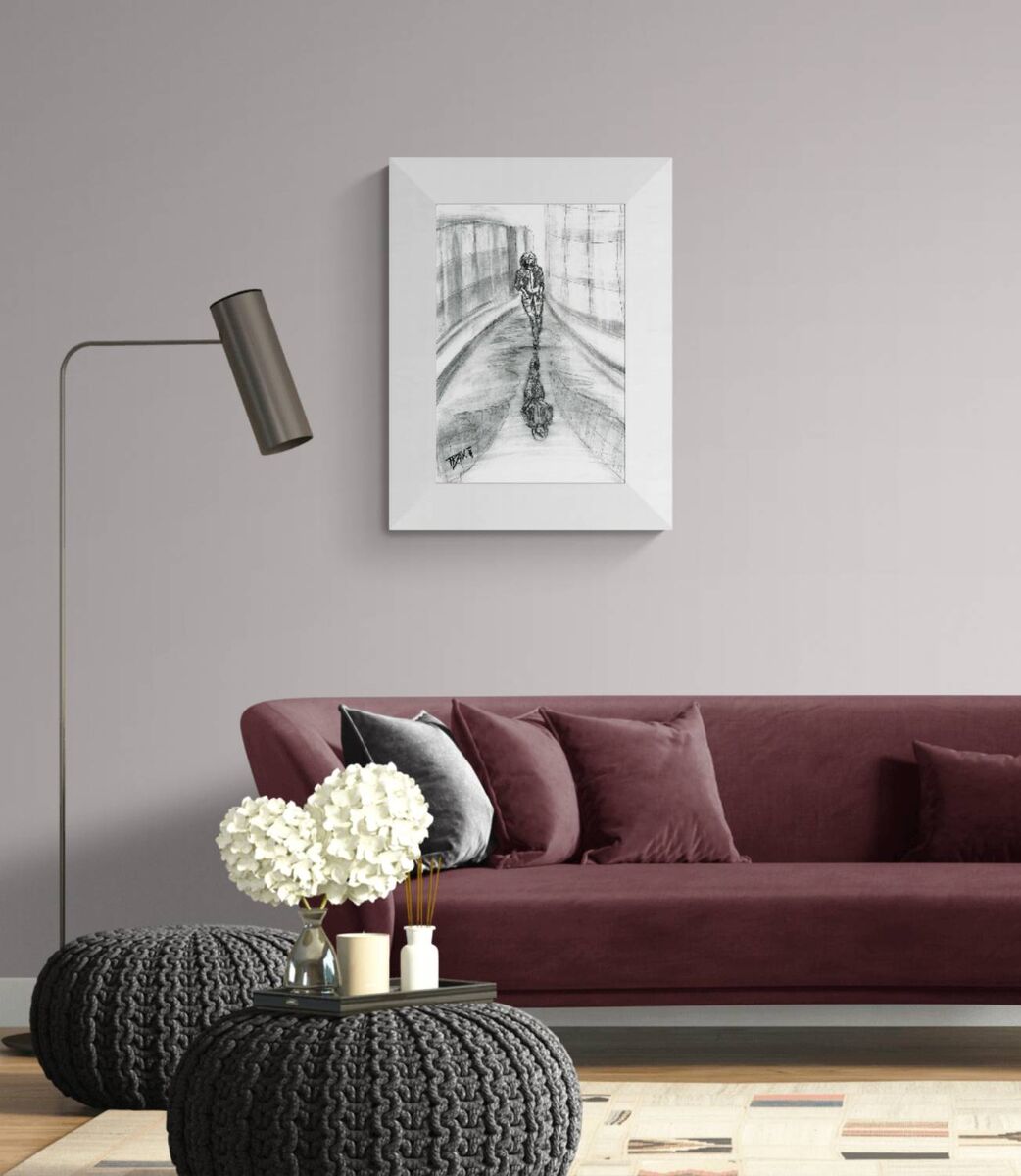 Original neo-noir urban charcoal drawing Alone with Myself by Diana Dimova TRAXI, featuring a woman and reflection exploring solitude in black and white. A framed black and white sketch print of a cyclist on a bridge, displayed on a light gray wall above a burgundy sofa in a modern living room setting.