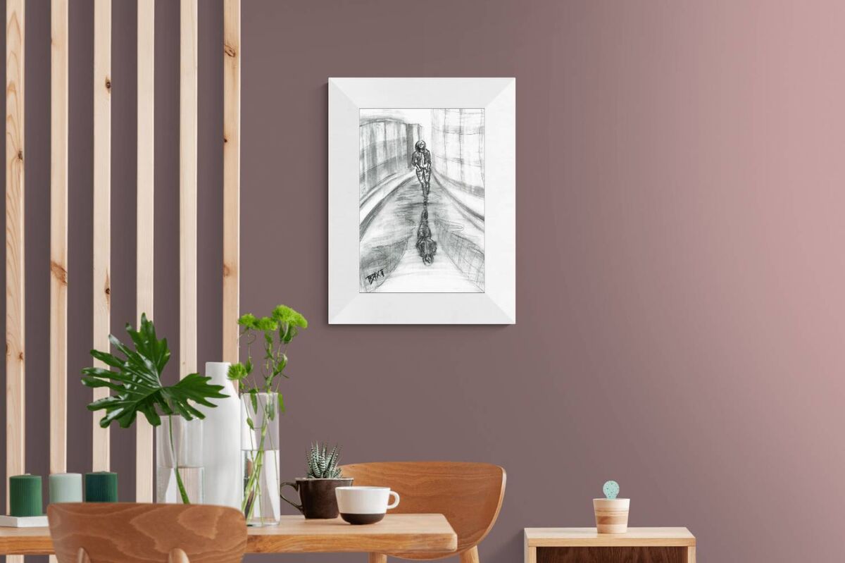 Original neo-noir urban charcoal drawing Alone with Myself by Diana Dimova TRAXI, featuring a woman and reflection exploring solitude in black and white. A framed black and white sketch print of a bicycle rider hanging on a dusty mauve wall in a modern dining room setting.