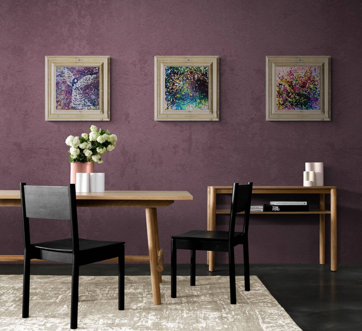 Original spiritual triptych Angelic Wall set by Diana Dimova TRAXI, featuring three connected fluid acrylic paintings representing protection and love. A styled interior scene with a purple textured wall, three framed abstract paintings, a wooden dining table, two black chairs, a side console, and a vase of white flowers.