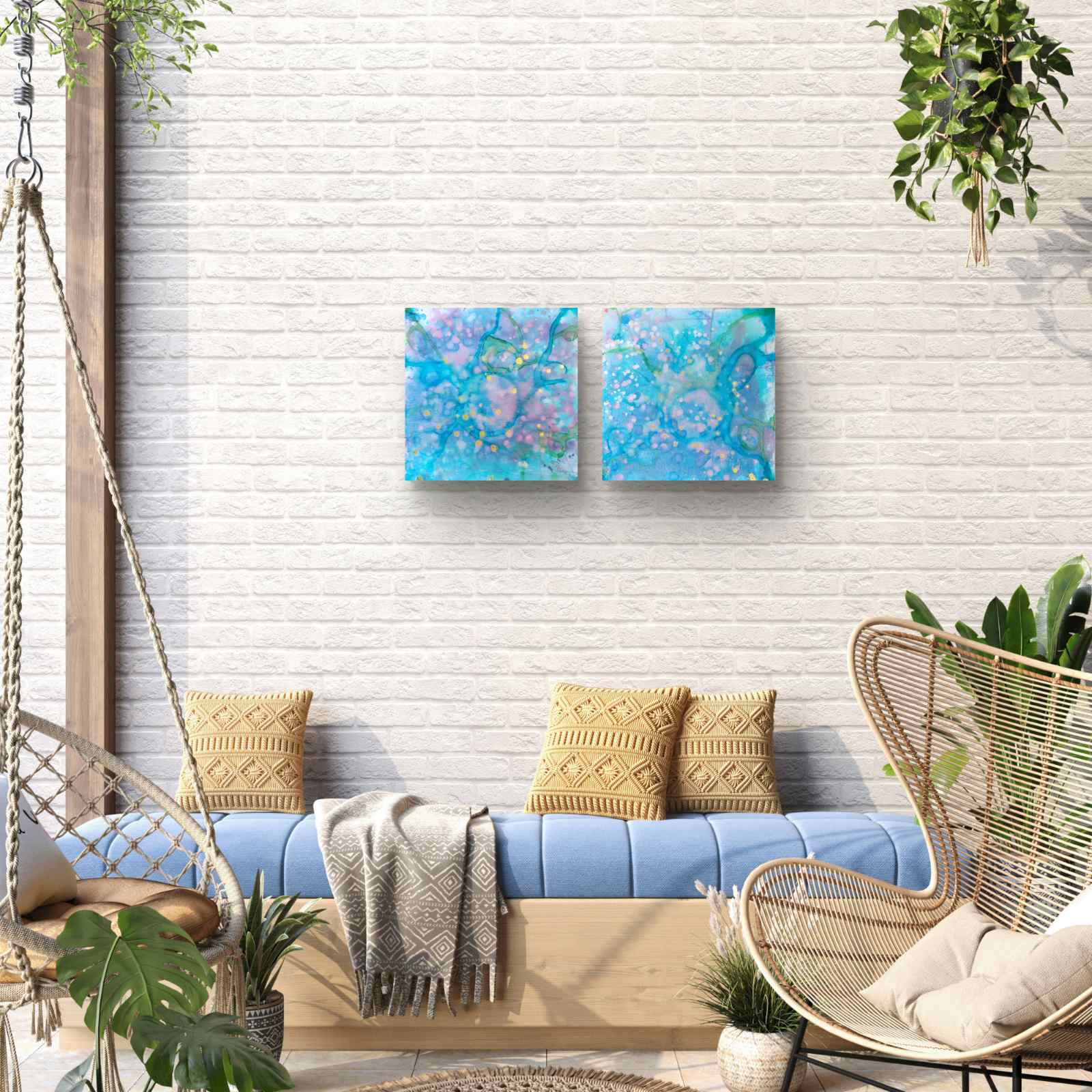 Original abstract diptych painting titled 'Rearrangement' by TRAXI, featuring textured layers in dialogue. The artwork explores themes of renewal, transition, and reconstruction through contemporary abstract expressionism. Two square abstract canvas prints with blue, purple, and teal swirls hanging side-by-side on a white brick wall above a blue bench with yellow pillows in a styled patio lounge setting.