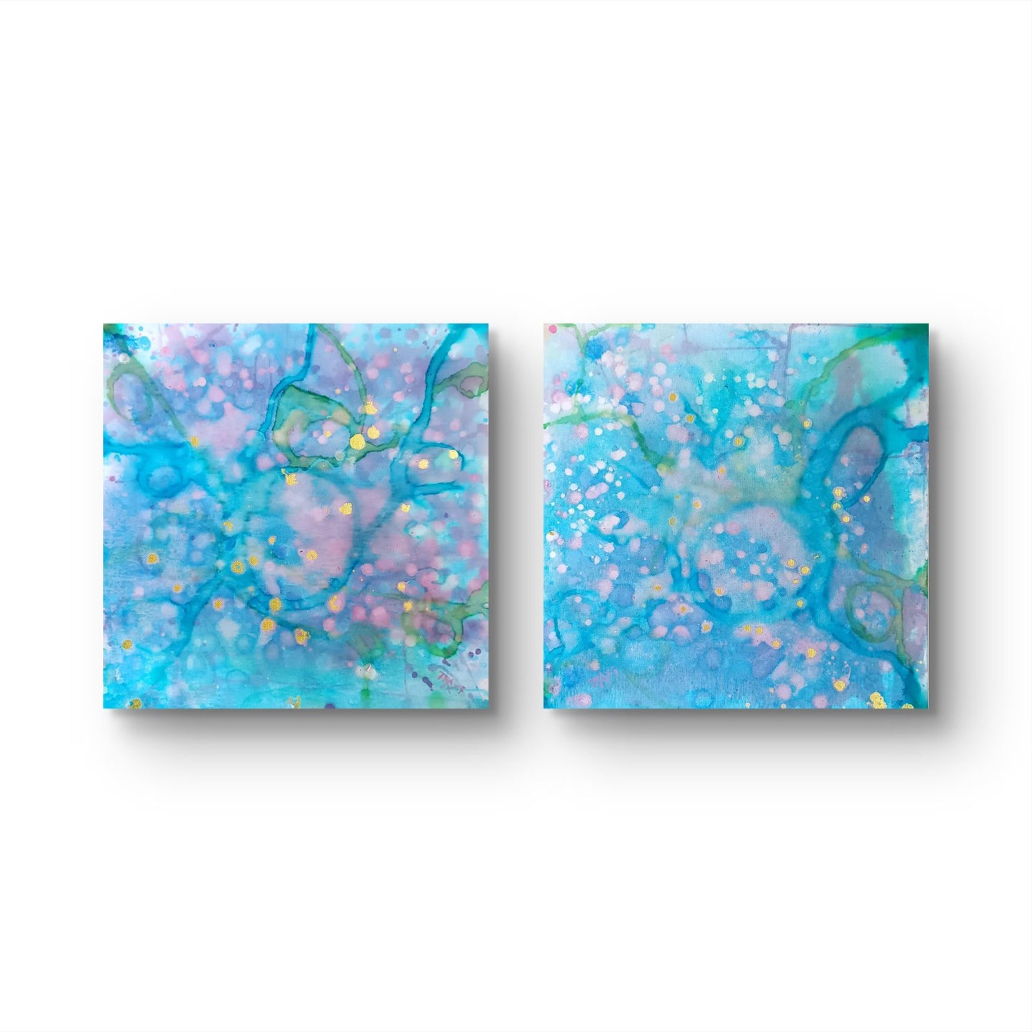 Original abstract diptych painting titled 'Rearrangement' by TRAXI, featuring textured layers in dialogue. The artwork explores themes of renewal, transition, and reconstruction through contemporary abstract expressionism. Two square abstract wall art panels with swirling blue, aqua, lavender, and pink patterns and small gold splatter details, shown side by side on a white background.