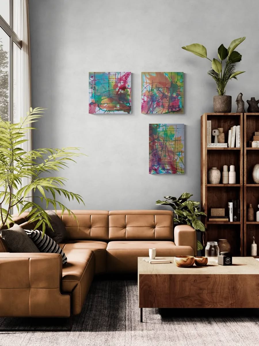 Half Complete collector edition fine art print portfolio featuring the five-artwork series States of Becoming by TRAXI, presented in a gallery-style presentation.Three colorful abstract canvas prints displayed on a light gray wall in a modern living room setting with a brown leather sectional sofa, wooden coffee table, and bookshelves.