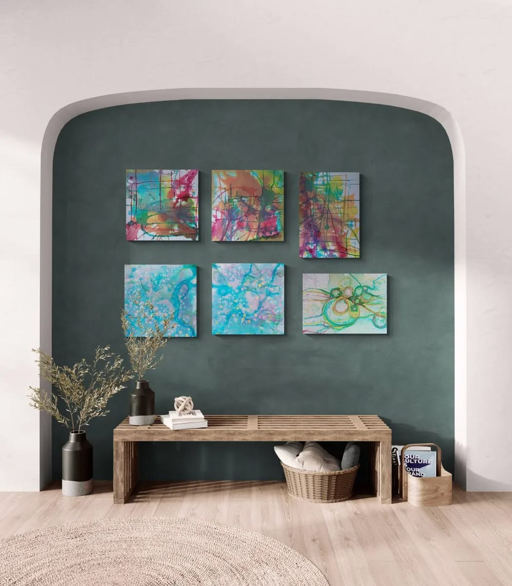 Complete collector edition fine art print portfolio featuring the five-artwork series States of Becoming by TRAXI, presented in a gallery-style presentation. A styled interior scene showing six colorful abstract canvas prints arranged on a dark green wall above a wooden bench, with vases, books, and a basket in a home setting.