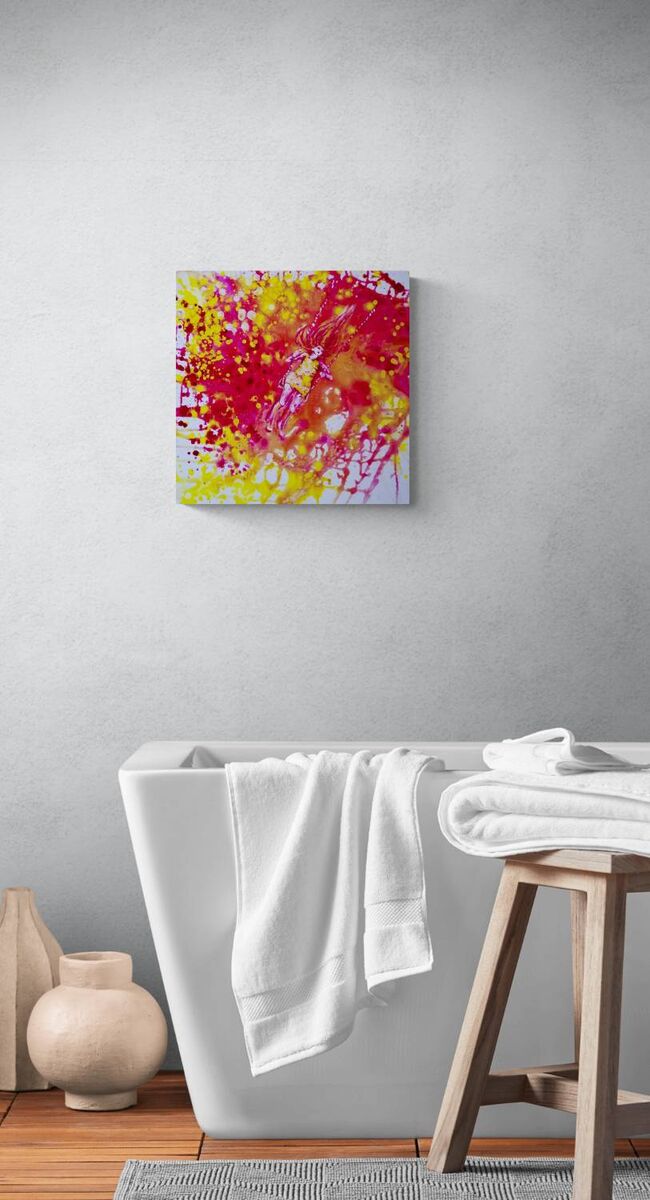 Sunshine Swing original fluid acrylic abstract painting by Diana Dimova TRAXI ART. Finalist Award winner 2022. Abstract wall art featuring vibrant splashes of red, yellow, and pink paint, displayed on a light gray wall above a modern white bathtub with white towels and a wooden stool.