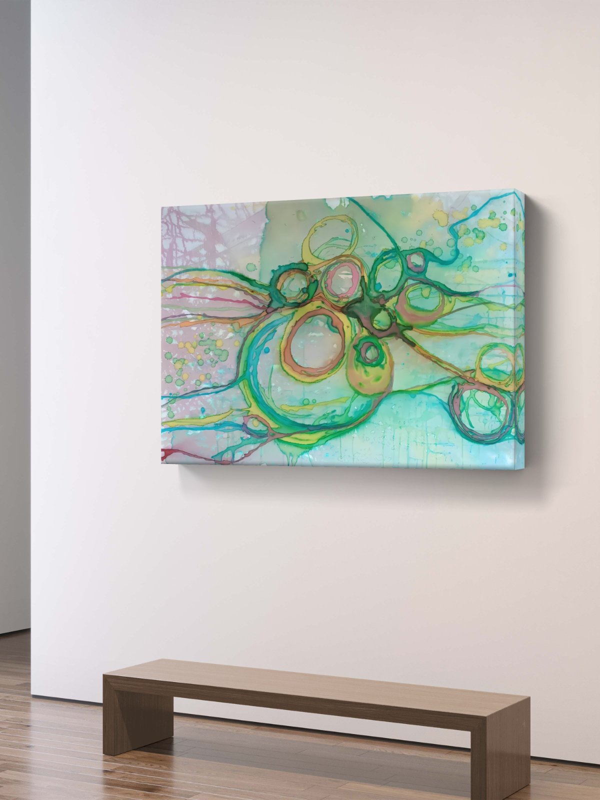 Original abstract painting titled 'The Balance' by TRAXI featuring serene textures and organic rhythms. The artwork represents the culmination of the series States of Becoming, exploring harmony, nature, and spiritual equilibrium. Abstract canvas wall art featuring green, yellow, and light blue circular brushstrokes, displayed on a white wall above a minimalist wooden bench.
