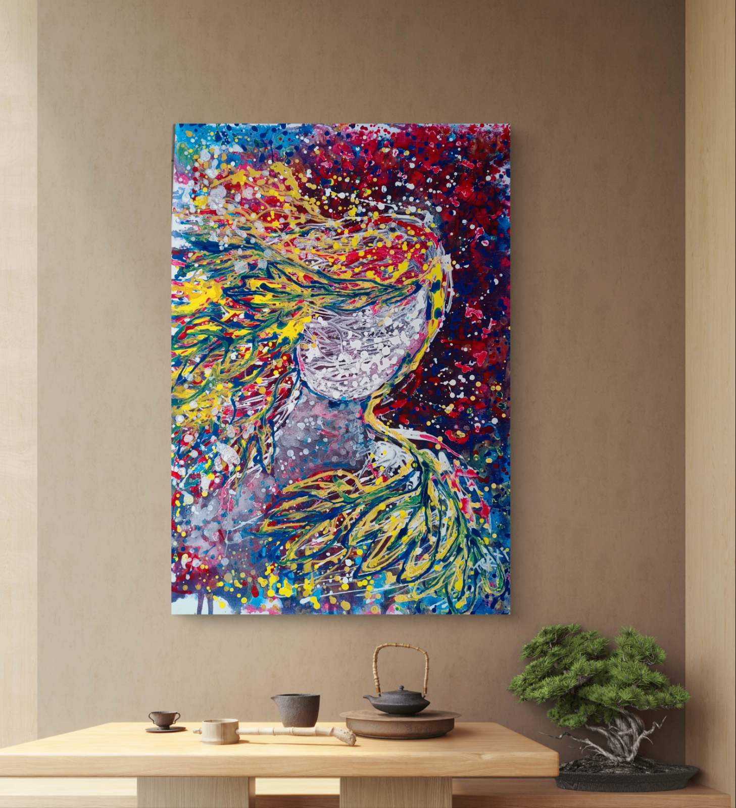 A colorful abstract canvas painting of a woman with flowing hair, displayed on a beige wall above a wooden table with tea items and a bonsai tree. Autumn’s Smile original abstract portrait fluid acrylic painting with warm burgundy, gold, and orange tones representing feminine autumn energy by Diana Dimova TRAXI ART.