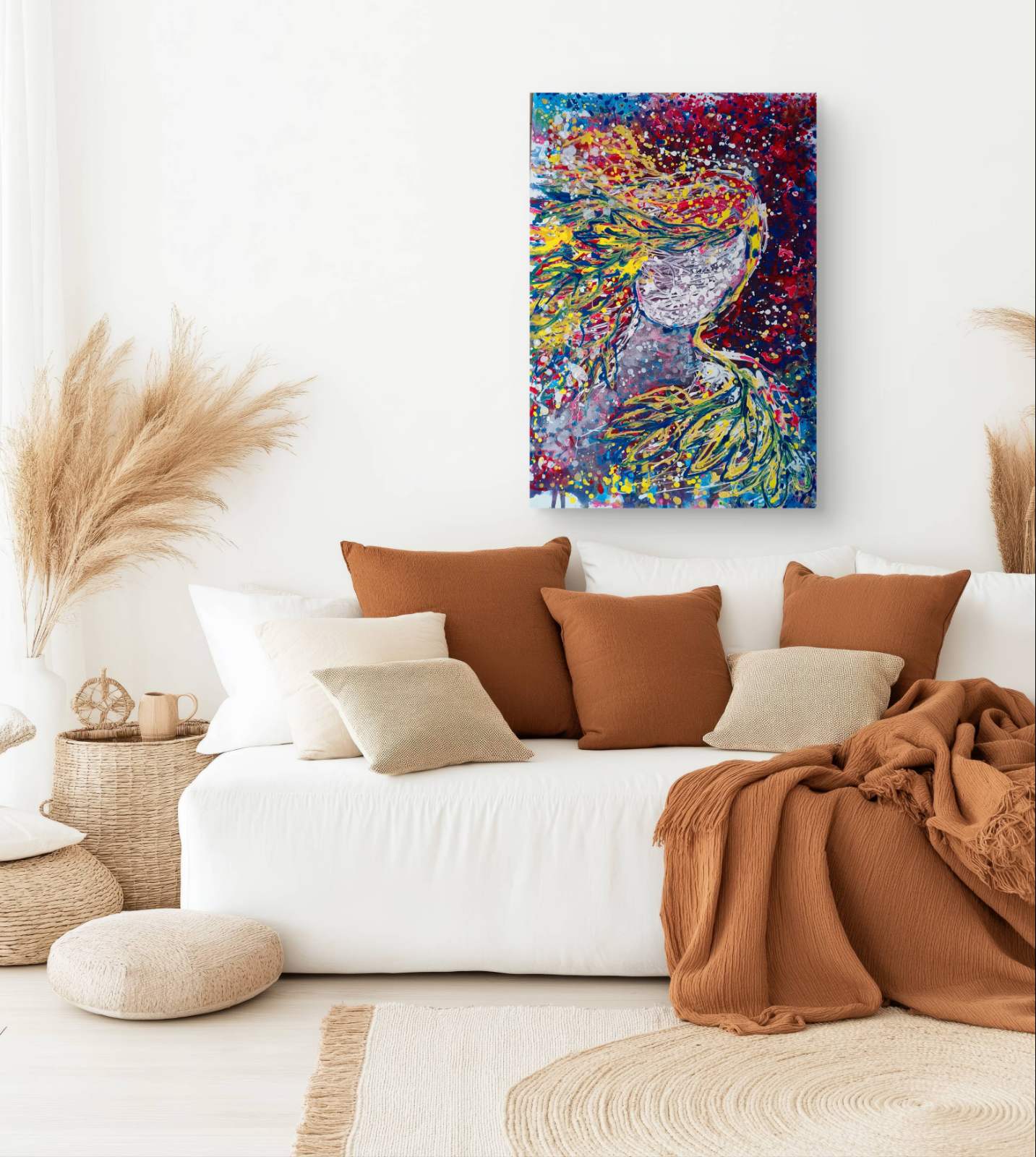 A colorful abstract canvas print of a peacock hanging on a white wall above a white sofa styled with brown and beige pillows, a rust-colored throw blanket, and dried pampas grass in a bright, modern living room. Autumn’s Smile original abstract portrait fluid acrylic painting with warm burgundy, gold, and orange tones representing feminine autumn energy by Diana Dimova TRAXI ART.