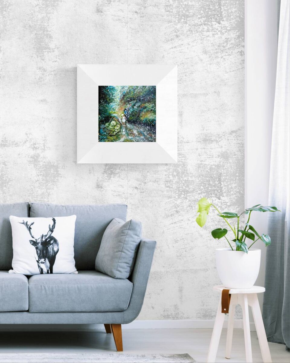 A framed square art print depicting a lush green forest stream hangs on a textured light gray wall above a blue-gray sofa with decorative pillows and a small potted plant on a stool.
By the River original impressionist oil painting with fresh green and white tones depicting a young girl by the river by Diana Dimova TRAXI ART.