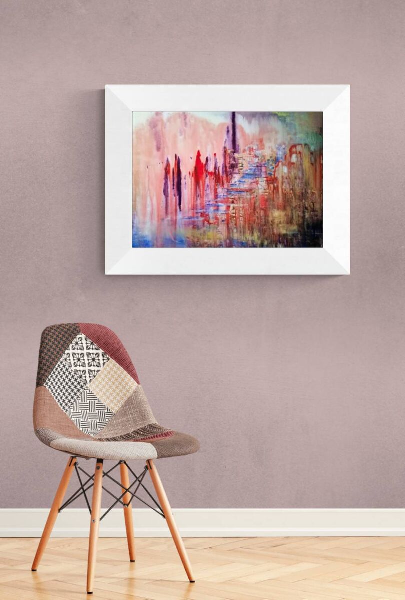 City of Memories original abstract lyrical fluid acrylic painting with dreamlike pink, violet, and orange tones representing nostalgia by Diana Dimova TRAXI ART. A framed abstract painting with a white frame hangs on a textured mauve wall above a modern patchwork chair with wooden legs.