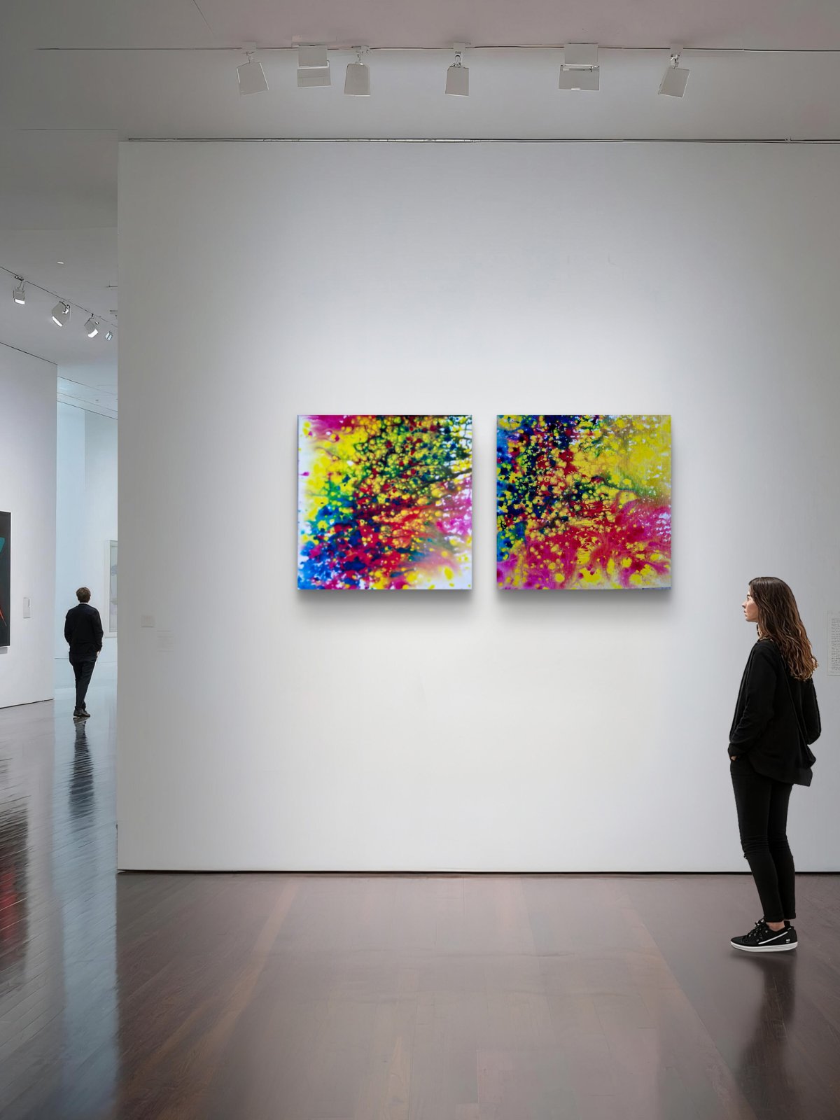 Fires Set original fluid acrylic abstract diptych in blue, red, orange, and yellow by Diana Dimova TRAXI ART. Finalist Award winner 2025. Two colorful abstract canvas paintings hang on a white gallery wall, with a woman standing to the right and a person walking in the distance on a polished dark wood floor.