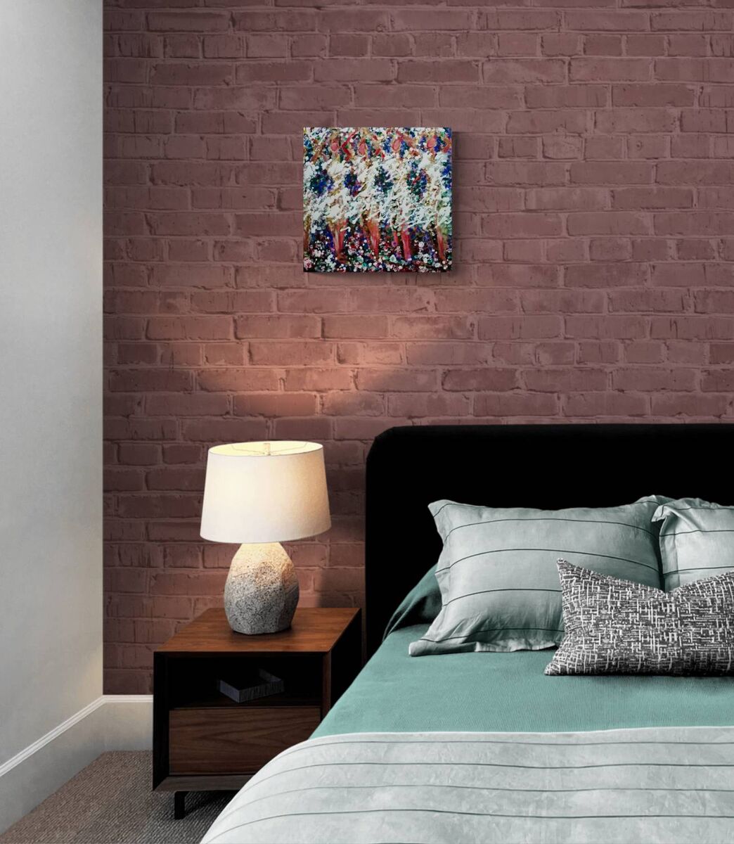 A styled bedroom scene featuring a square abstract canvas art print hanging on a brick wall above a bed with teal bedding and a wooden nightstand with a lamp.In Spring the Trees Dance original abstract ballerina spring landscape fluid acrylic painting with deep burgundy, blue, and white tones representing plum trees in Bulgaria by Diana Dimova TRAXI ART.