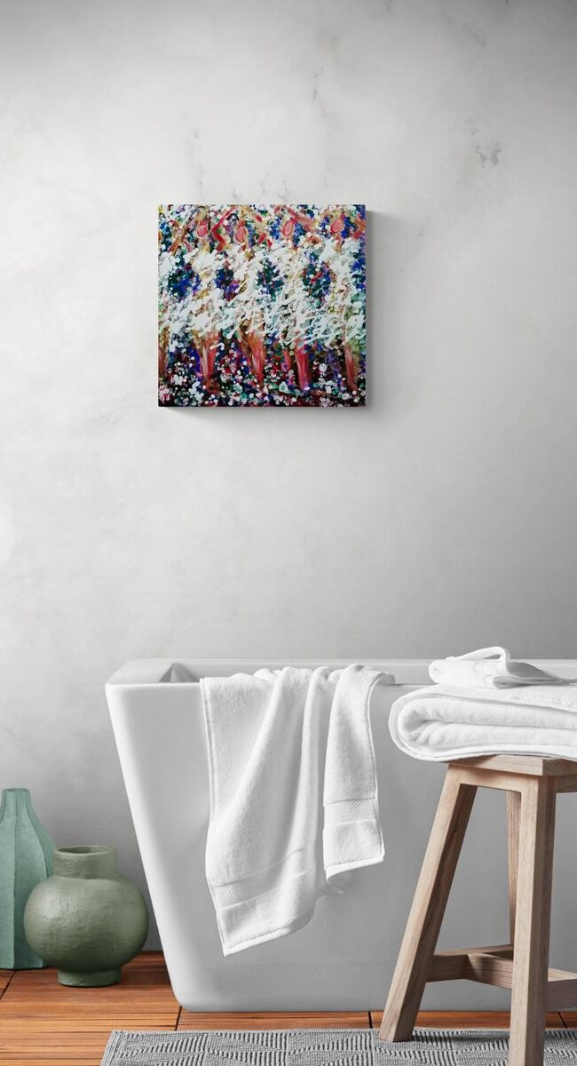 A colorful abstract canvas art print hangs on a light gray textured wall above a white freestanding bathtub with white towels, a wooden stool, and green ceramic vases on a wood floor. In Spring the Trees Dance original abstract ballerina spring landscape fluid acrylic painting with deep burgundy, blue, and white tones representing plum trees in Bulgaria by Diana Dimova TRAXI ART.