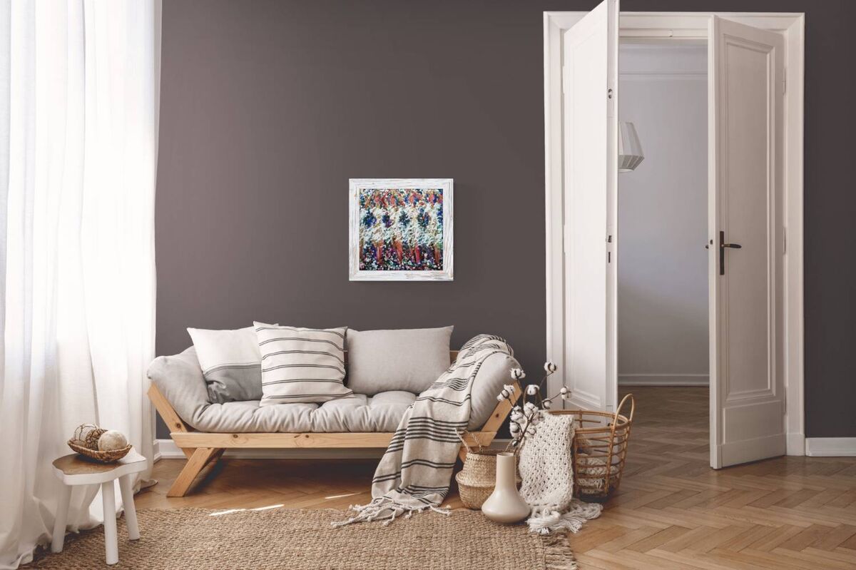 A styled interior room scene with a low wooden daybed, neutral pillows, a striped throw blanket, a woven rug, and a framed abstract artwork on a dark gray wall. An open doorway and white curtains are visible, along with decorative baskets and vases on the floor. In Spring the Trees Dance original abstract ballerina spring landscape fluid acrylic painting with deep burgundy, blue, and white tones representing plum trees in Bulgaria by Diana Dimova TRAXI ART.