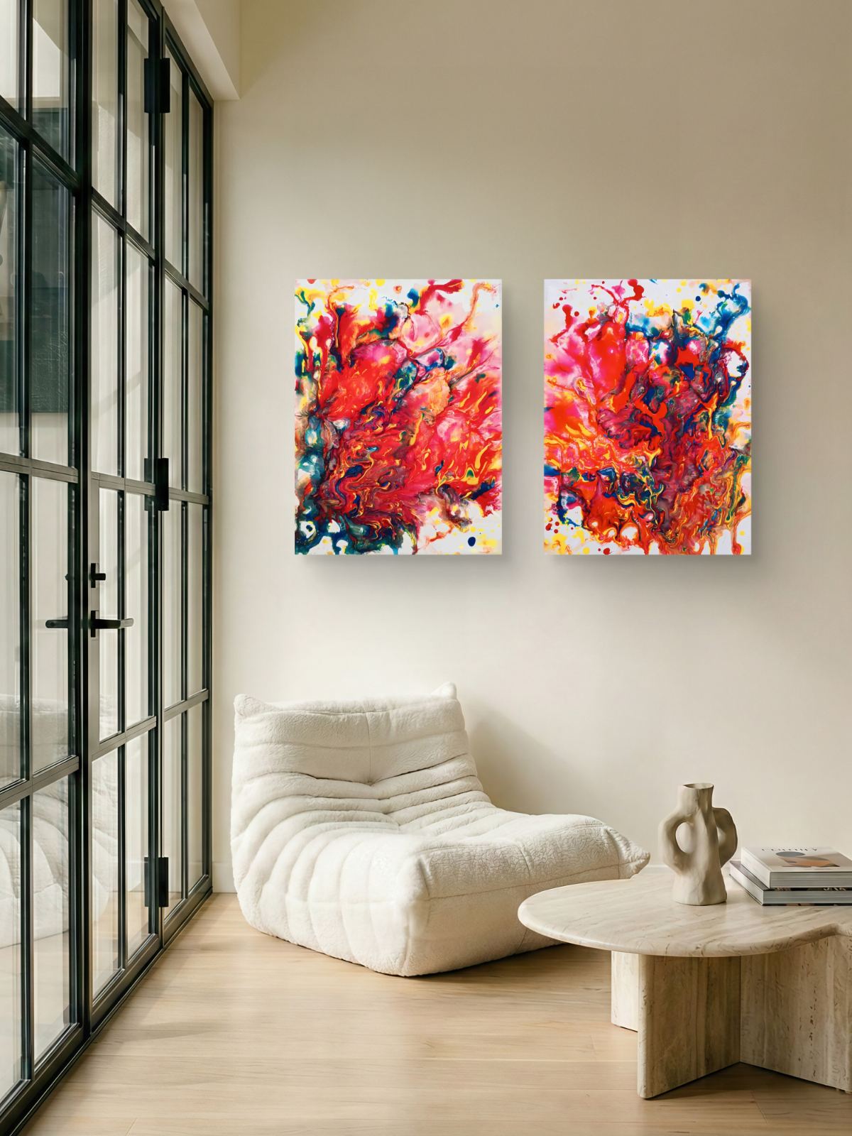 Magic Set large scale limited edition diptych print featuring bold red fluid abstract shapes by Diana Dimova TRAXI ART. Two square abstract canvas prints with vibrant red, orange, pink, and blue brushstrokes hanging side-by-side on a beige wall in a modern living room setting with a white lounge chair and a small round wooden table.