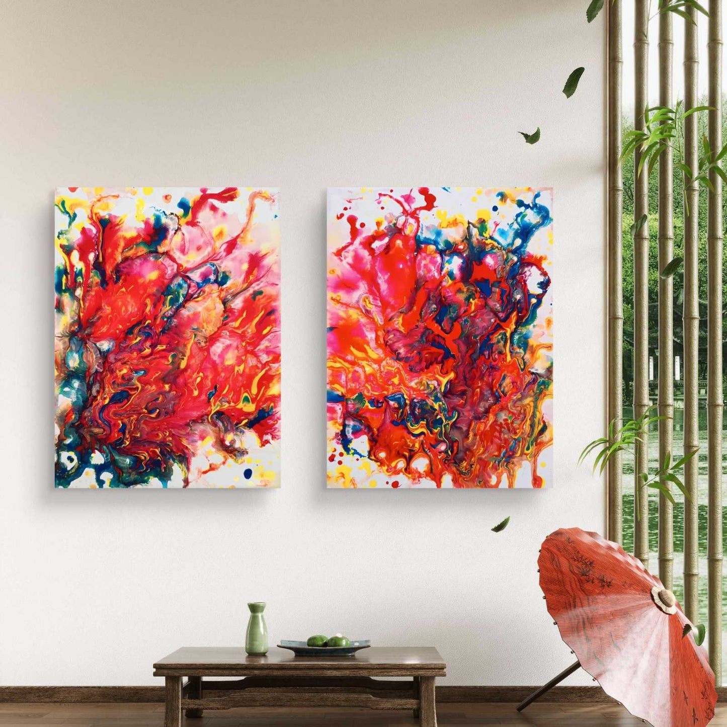 Magic Set large scale limited edition diptych print featuring bold red fluid abstract shapes by Diana Dimova TRAXI ART. Two vertical abstract canvas wall art prints with vibrant red, orange, pink, yellow, blue, and white paint splashes, displayed side-by-side on a white wall in a styled room with a wooden table, green vase, and bamboo blinds.
