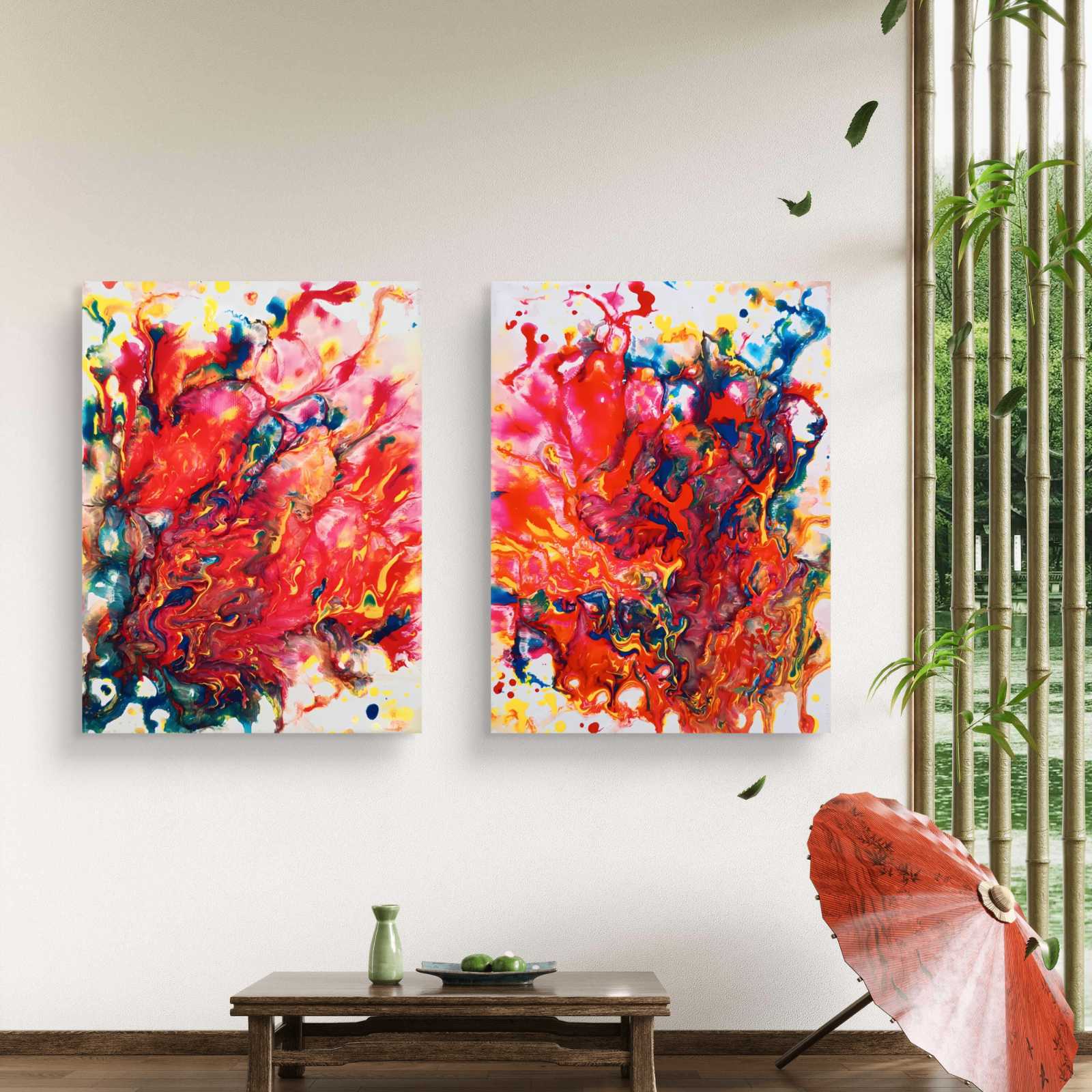 Magic Set large scale limited edition diptych print featuring bold red fluid abstract shapes by Diana Dimova TRAXI ART. Two vertical abstract canvas wall art prints with vibrant red, orange, pink, yellow, blue, and white paint splashes, displayed side-by-side on a white wall in a styled room with a wooden table, green vase, and bamboo blinds.