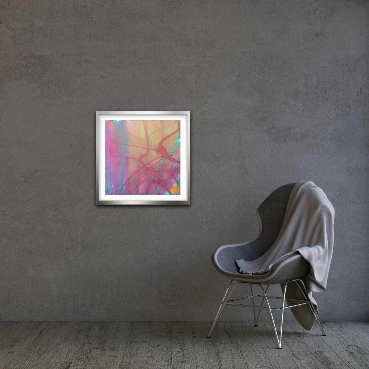 Nuances of Time original abstract mixed media square painting with soft pastel pink and violet tones by Diana Dimova TRAXI ART. A framed abstract art print with vibrant pink, orange, and blue brushstrokes hangs on a textured gray wall next to a modern gray chair with a draped white throw blanket.