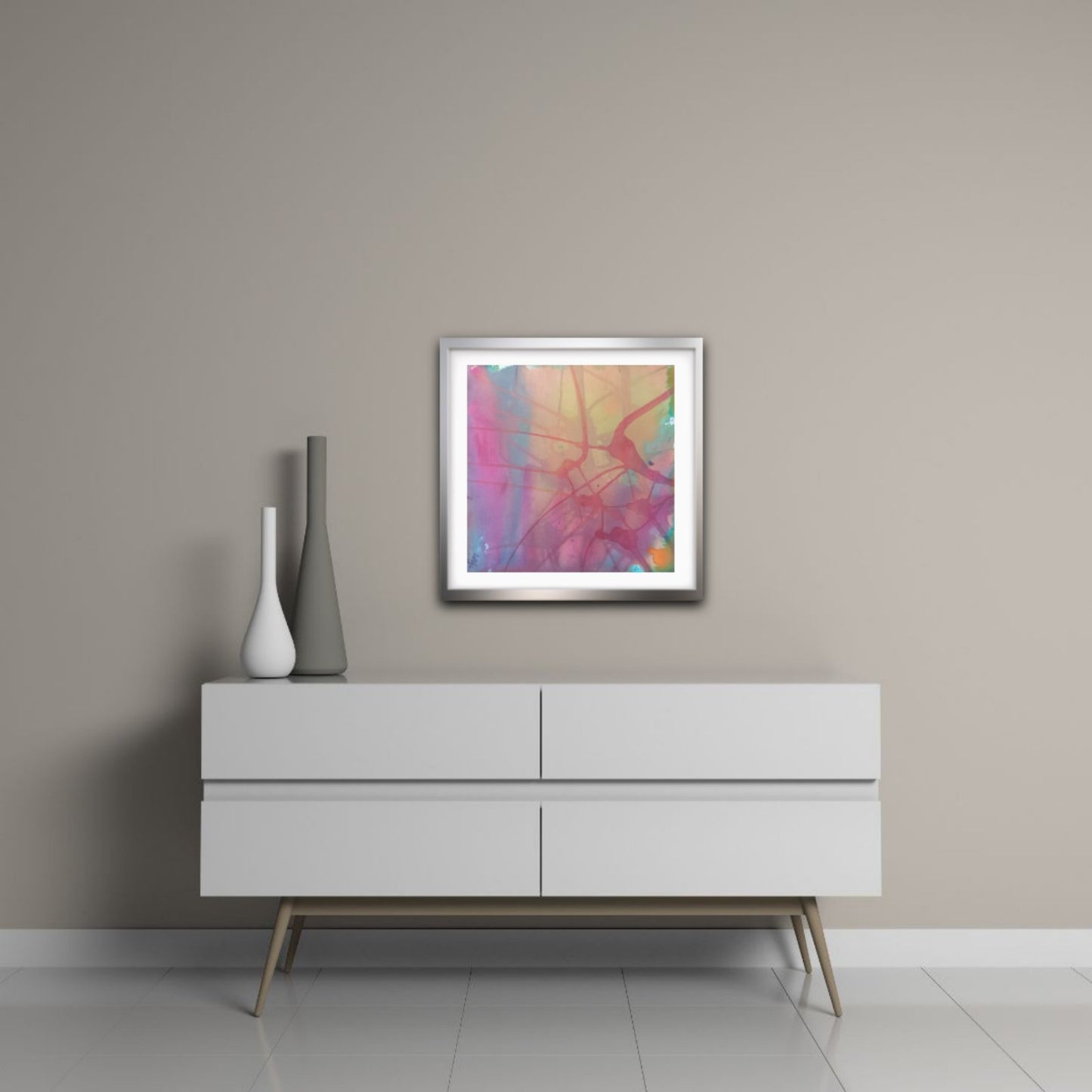  Nuances of Time original abstract mixed media square painting with soft pastel pink and violet tones by Diana Dimova TRAXI ART. A square framed abstract art print with vibrant pink, purple, orange, and yellow brushstrokes, displayed on a light gray wall above a modern white sideboard with decorative vases.