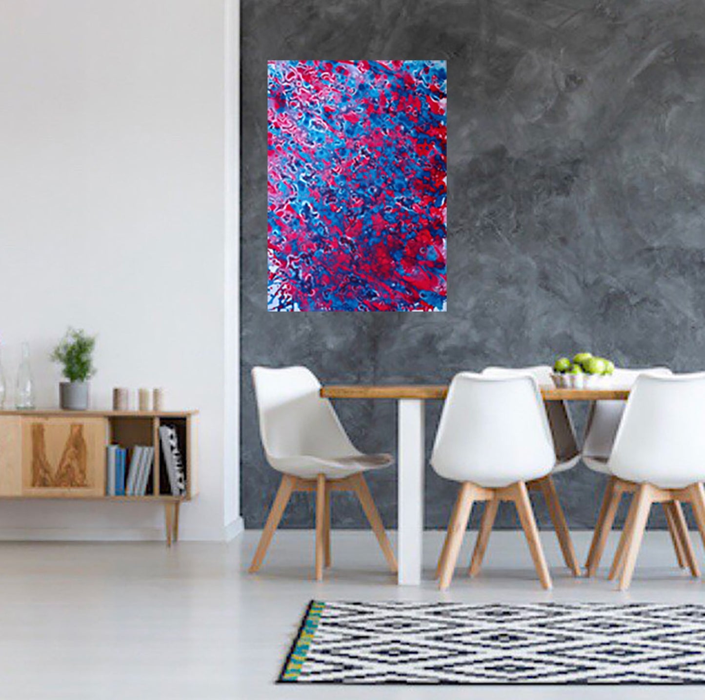 Red & Blue Balance original fluid acrylic abstract painting by Diana Dimova TRAXI ART. A colorful abstract canvas print with vibrant red, pink, and blue brushstrokes, displayed on a dark gray textured wall in a modern dining room setting.