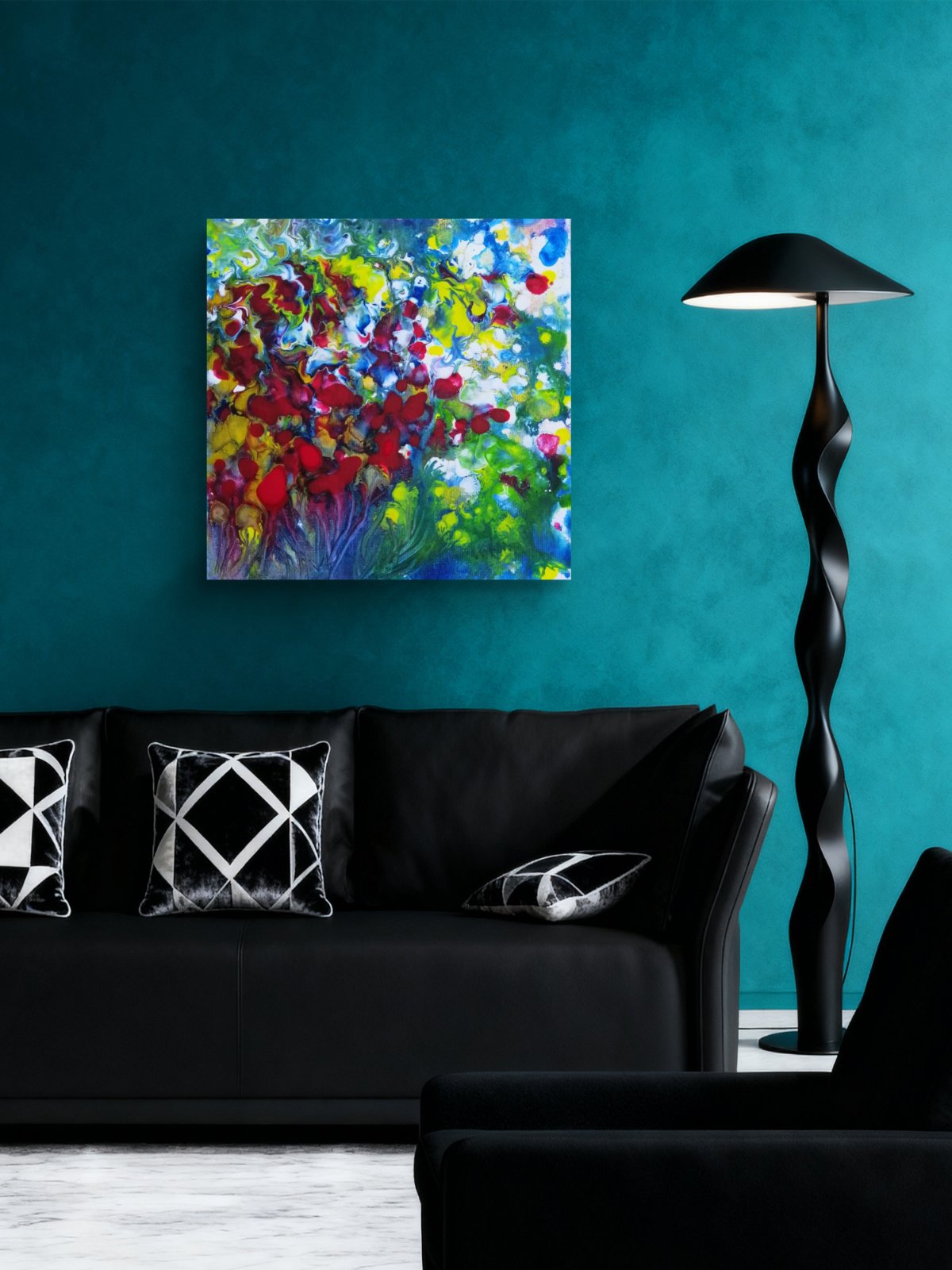 A colorful abstract canvas painting with vibrant red, yellow, green, and blue brushstrokes, displayed on a textured teal wall above a black sofa in a modern living room setting. Red Flowers limited edition premium square canvas print with vibrant red, green, and white fluid acrylic tones by Diana Dimova TRAXI ART.