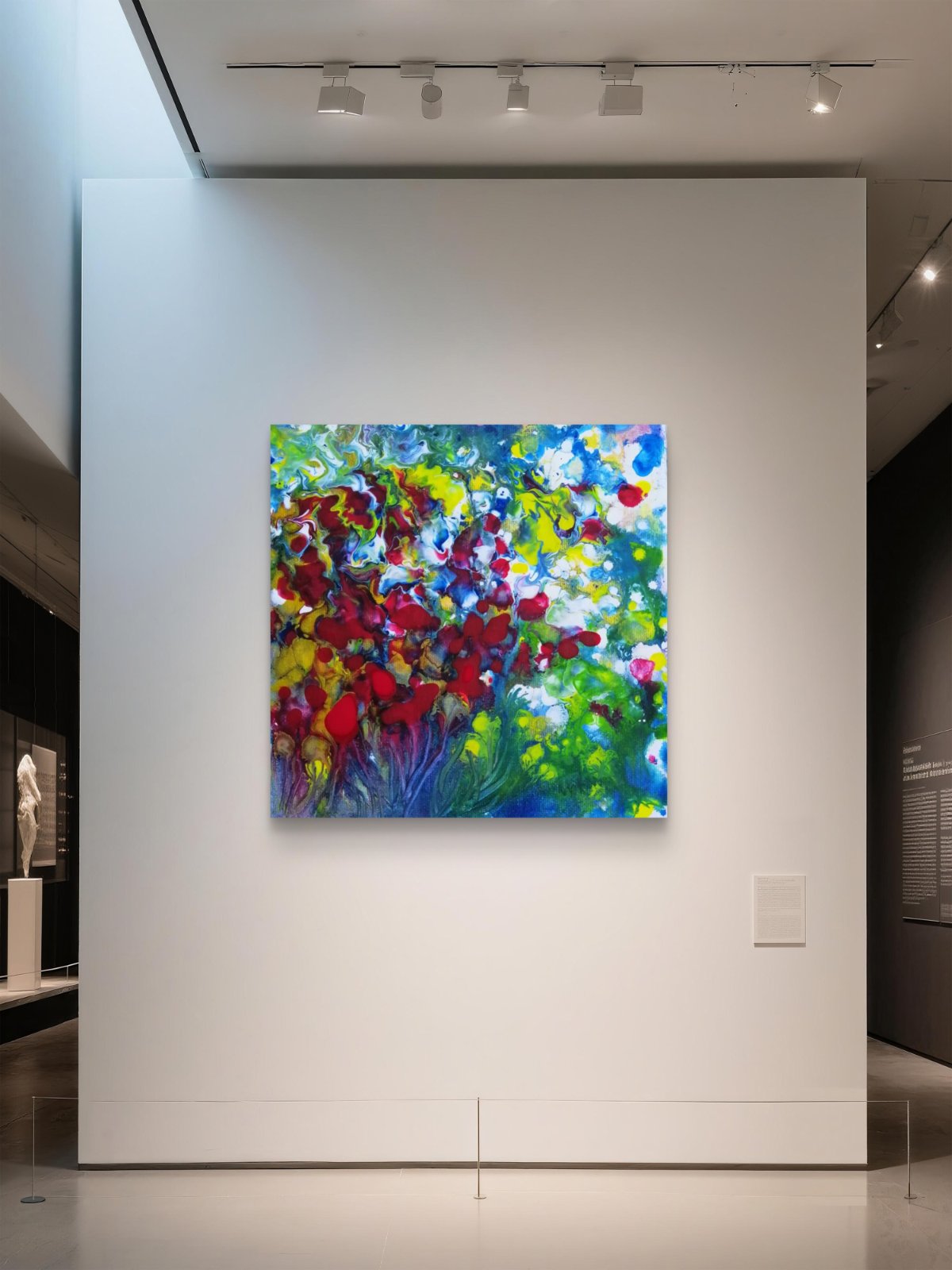 A colorful abstract floral painting with red, yellow, green, and blue brushstrokes, displayed on a white gallery wall under track lighting. Red Flowers limited edition premium square canvas print with vibrant red, green, and white fluid acrylic tones by Diana Dimova TRAXI ART.