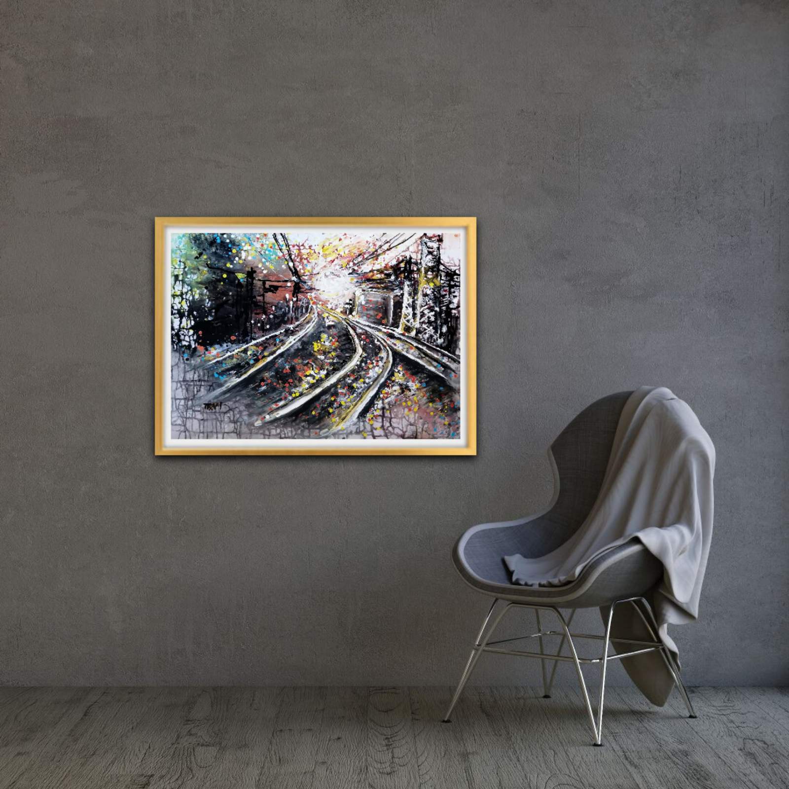 A framed abstract painting of train tracks is displayed on a textured gray wall in a modern room setting, next to a gray chair with a light gray throw blanket. The Call of the Rails original abstract urban landscape fluid acrylic painting with minimalist black, brown, and white tones representing railway lines by Diana Dimova TRAXI ART.