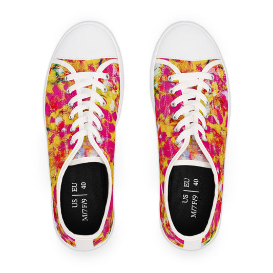 Women's low top sneakers of happiness featuring abstract wearable art inspired by the painting Summer Flowers by Diana Dimova TRAXI. A pair of low-top canvas sneakers shown from a top-down view on a white background. The shoes feature a vibrant, multicolored paint-splatter pattern in pink, yellow, and orange, with white laces, white rubber toe caps, and black insoles.