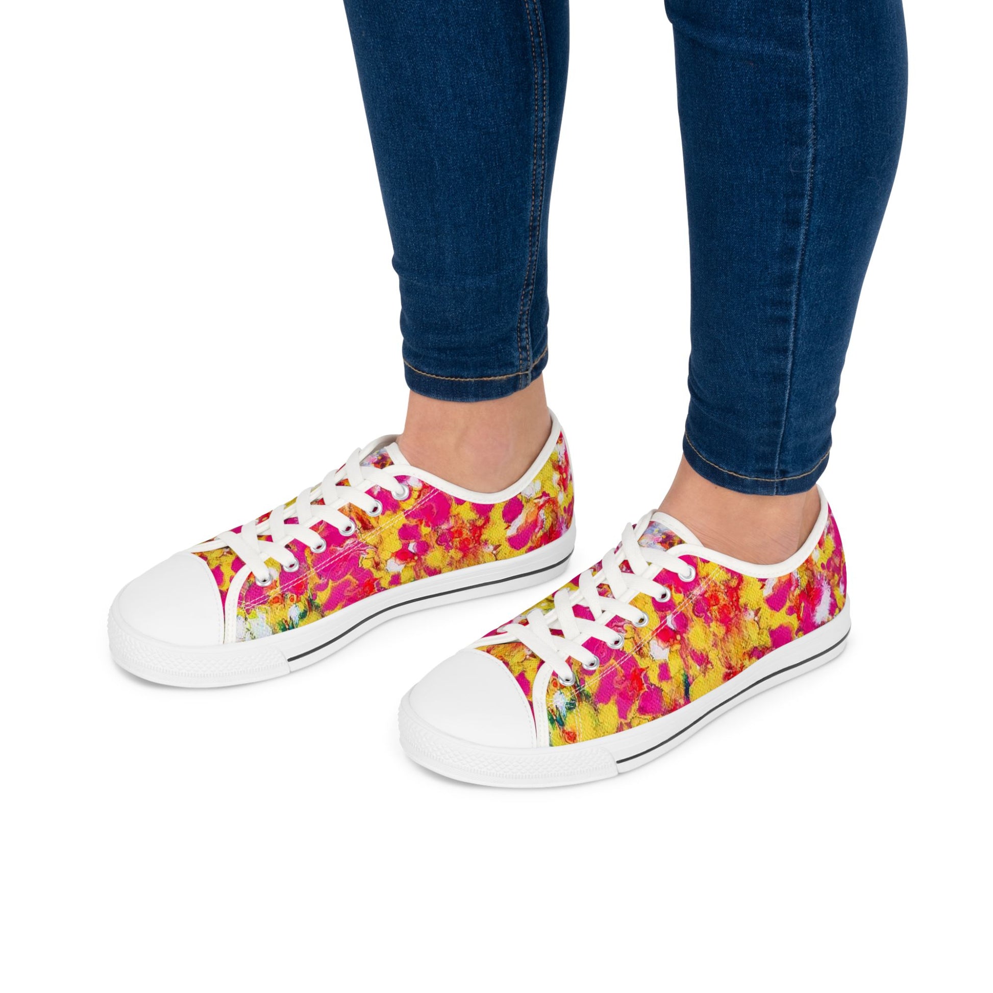 Women's low top sneakers of happiness featuring abstract wearable art inspired by the painting Summer Flowers by Diana Dimova TRAXI. A pair of low-top canvas sneakers with a red and white patterned upper, white laces, and white rubber toe caps, shown on a model wearing blue jeans against a white background.