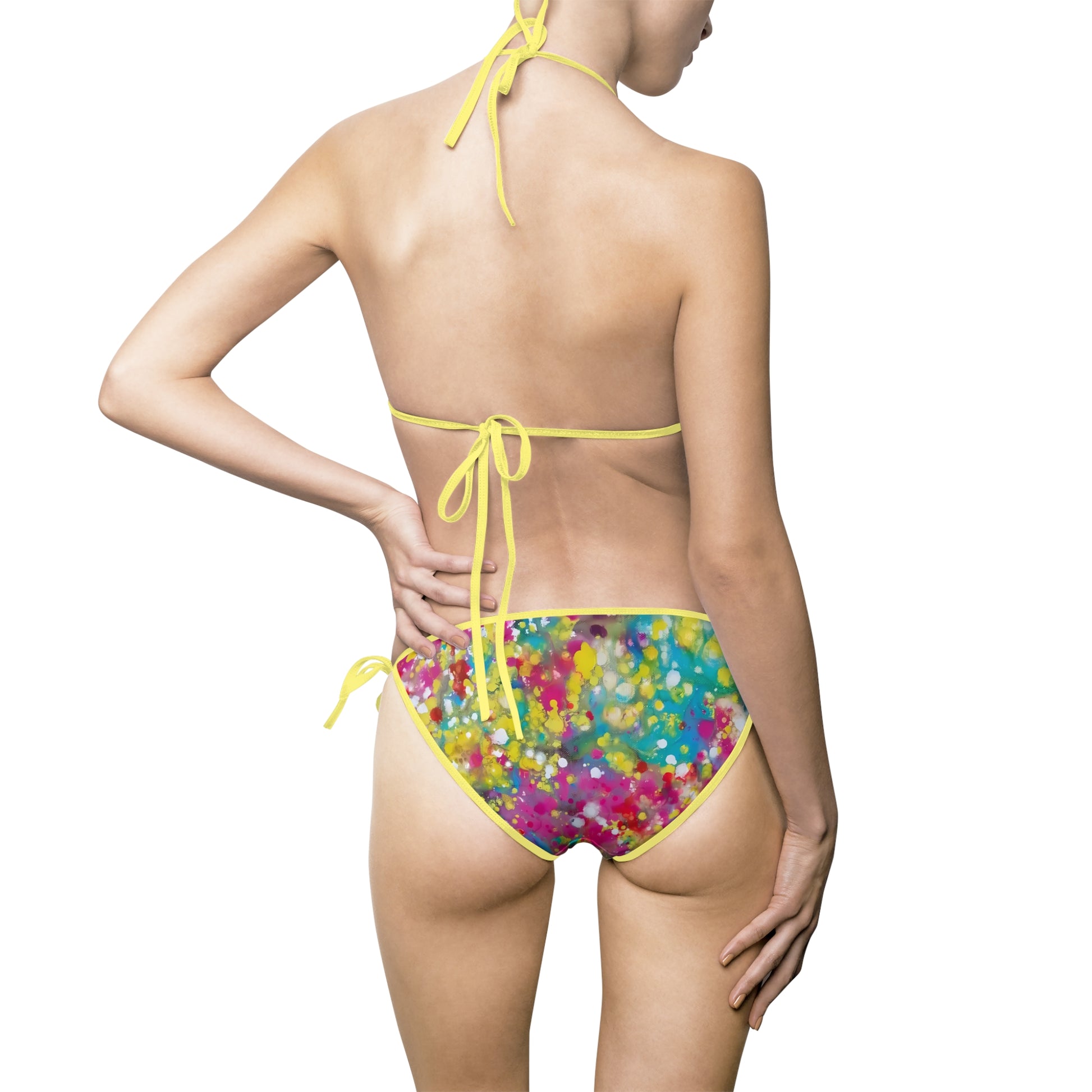 Women's summer bikini swimsuit of happiness featuring abstract wearable art inspired by the Paintings of Happiness series by Diana Dimova TRAXI. A model shown from the back wearing a two-piece bikini. The bikini bottoms feature a vibrant, multicolored abstract paint splatter pattern with a bright yellow trim and side ties.